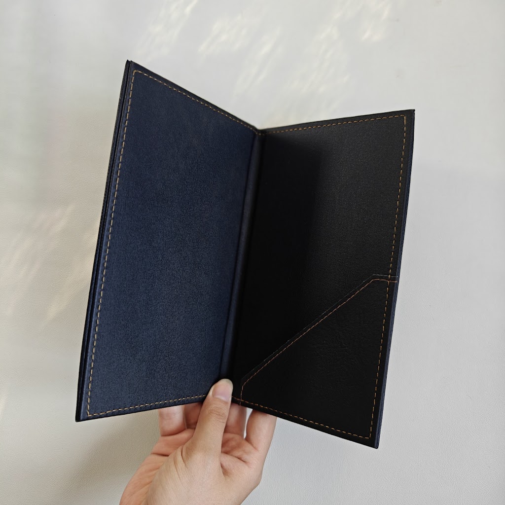 Hand holding open black bill presenter showing single diagonal pocket