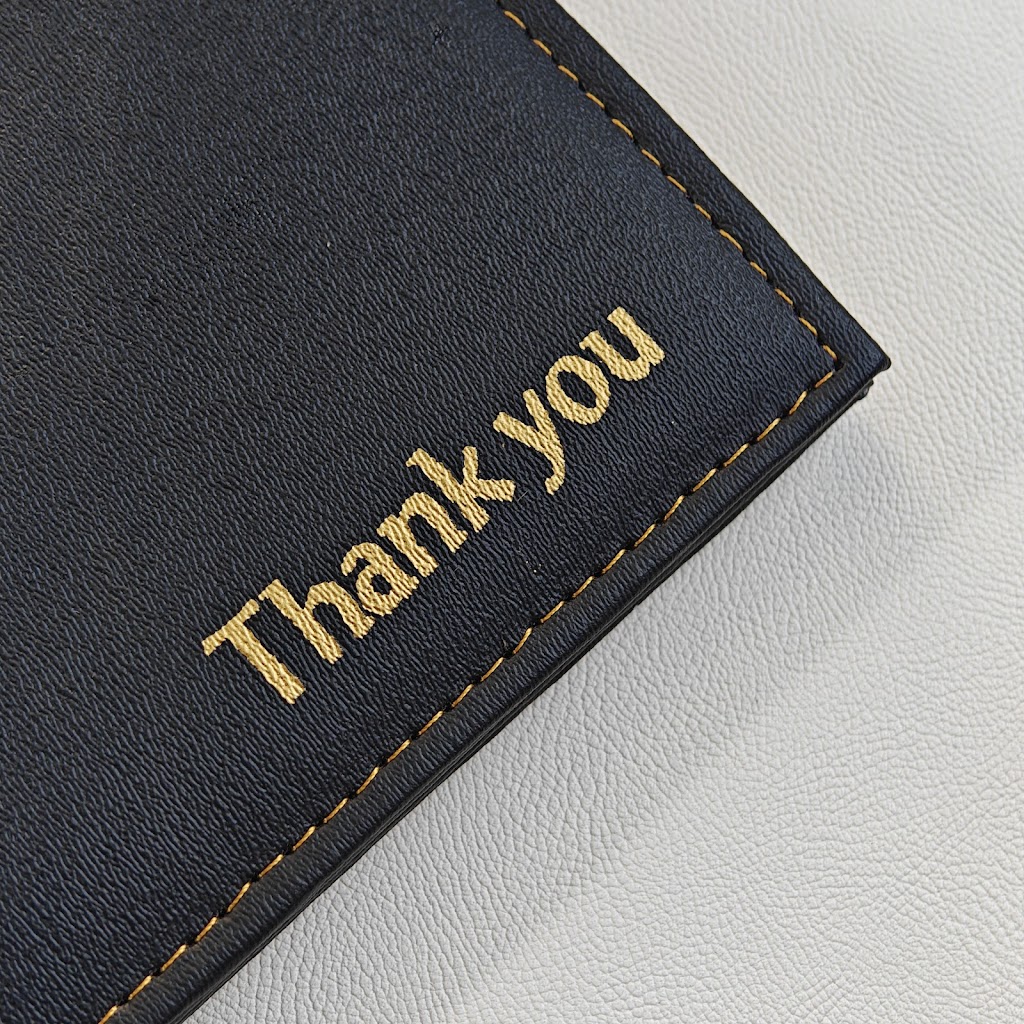 Closeup of gold "Thank you" embossing and contrast stitching on black leather