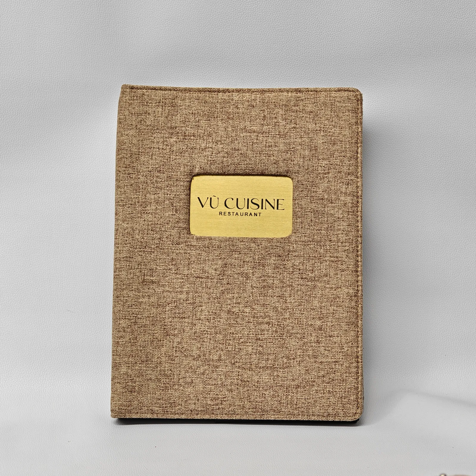 Canvas menu cover detail showing embossed branding and geometric corner accents