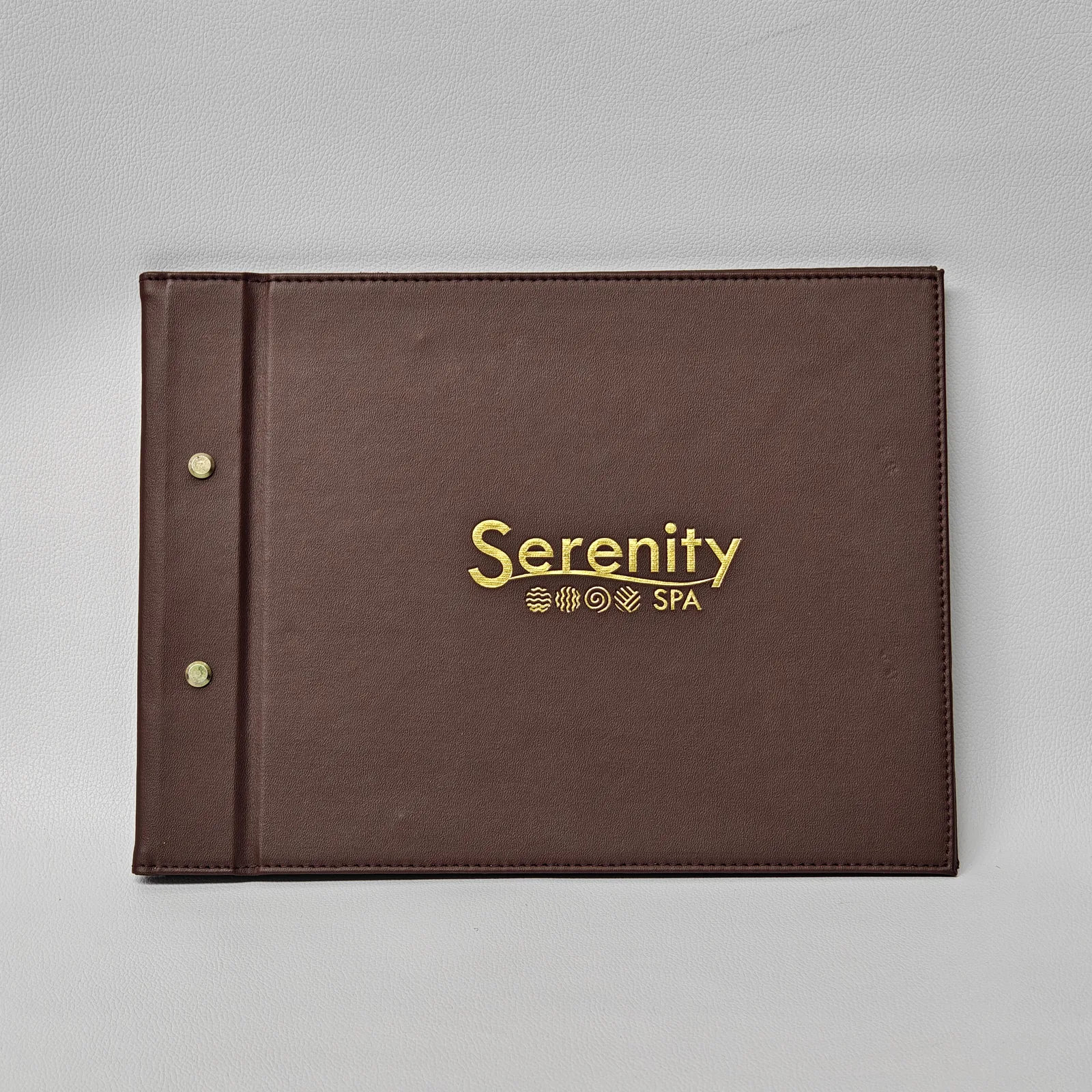 Brown leather A4 menu cover with snap buttons and embossed spa branding