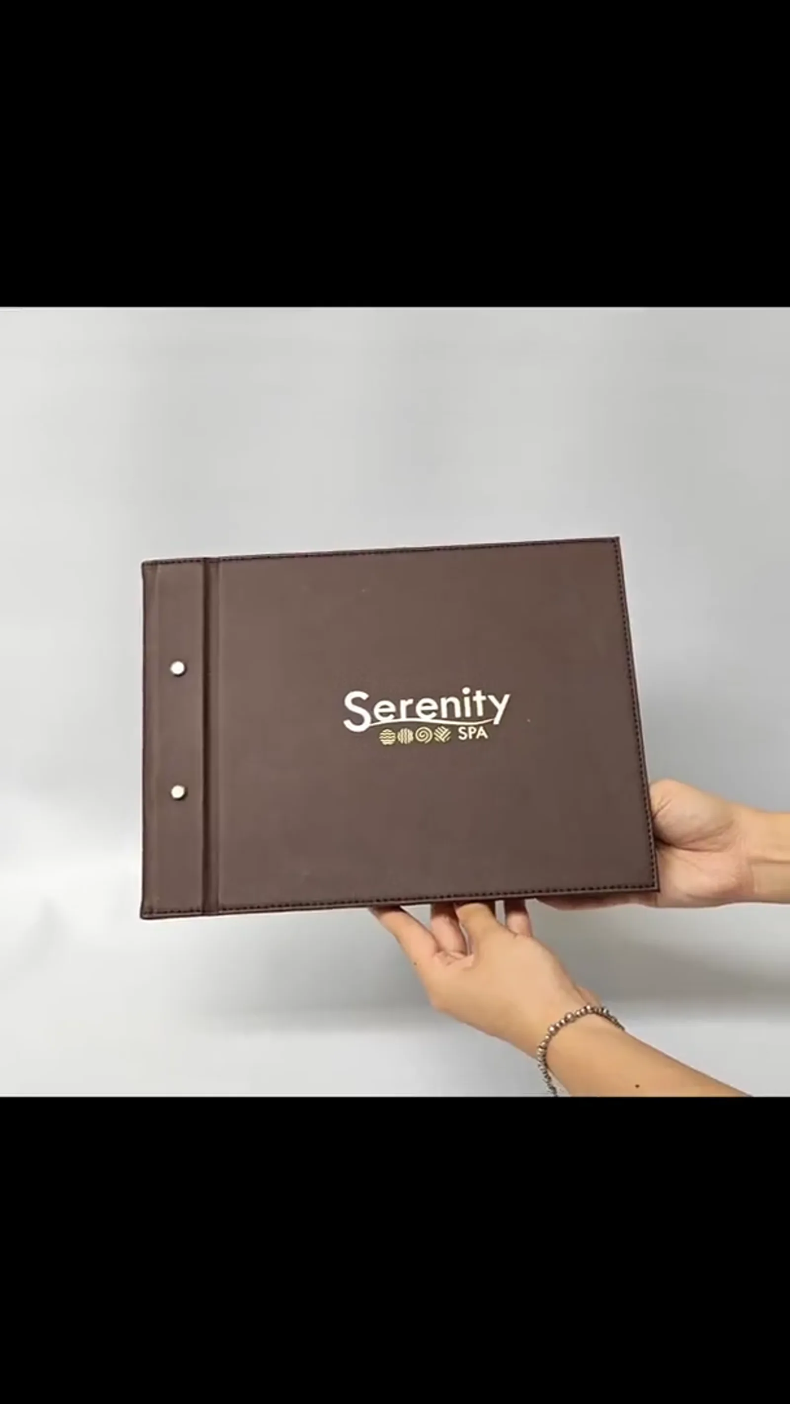 Demonstration of open leather menu cover showing ring-binder mechanism and interior