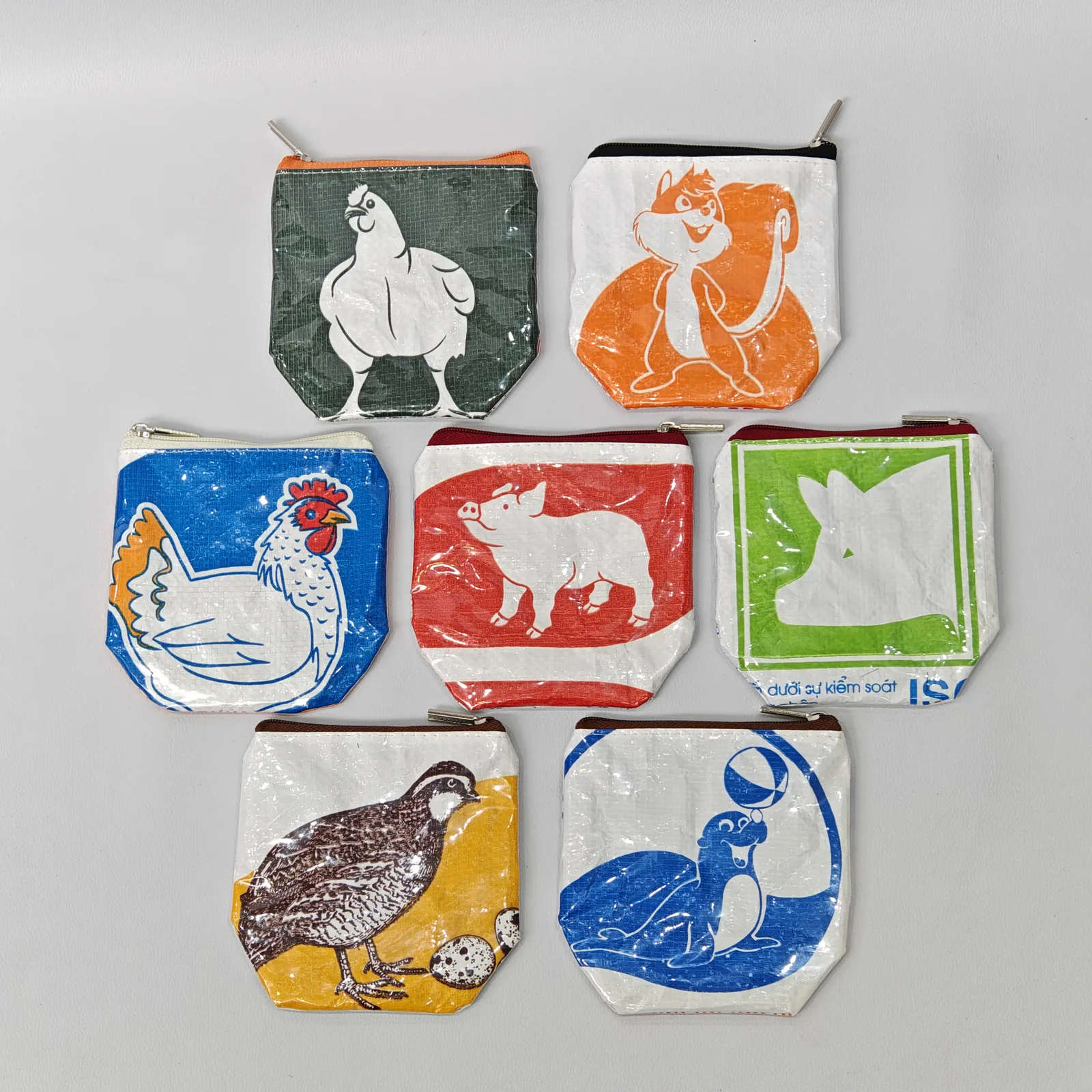 Collection of eight animal-print canvas pouches in vibrant colors with coordinating metal zippers