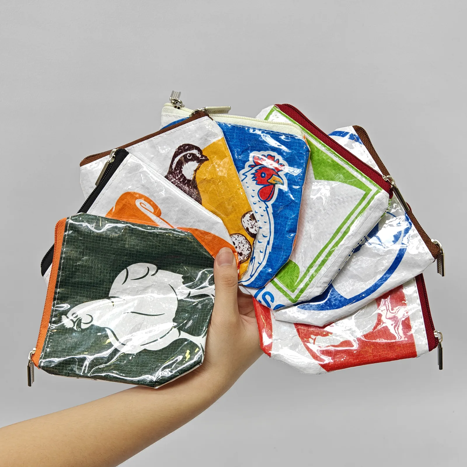Hand holding orange monkey pouch containing small item, showing compact size and capacity