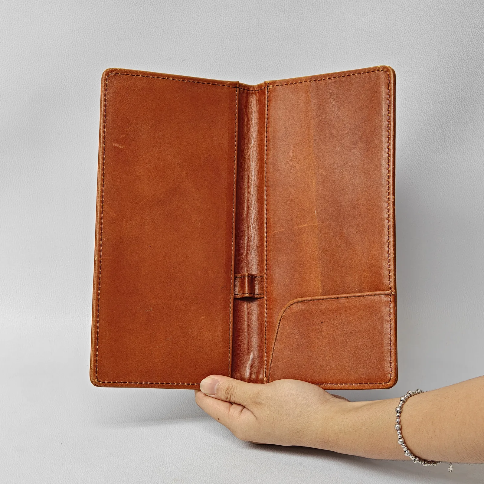 Open interior of a brown leather folder featuring a large side pocket and a central pen loop.