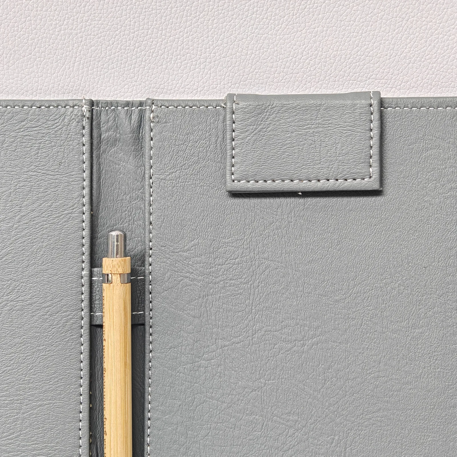 Pen holder detail with white stitching and wooden accent