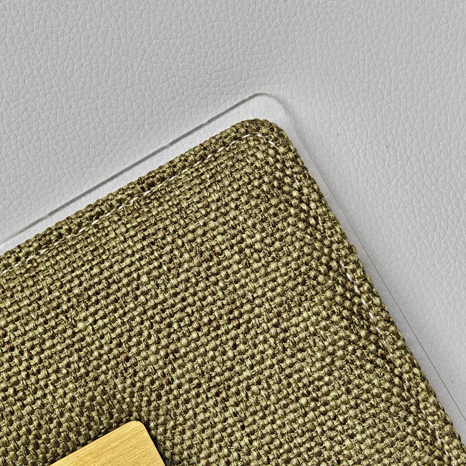 Close-up of the textured woven fabric and white stitching on the corner of a menu cover.