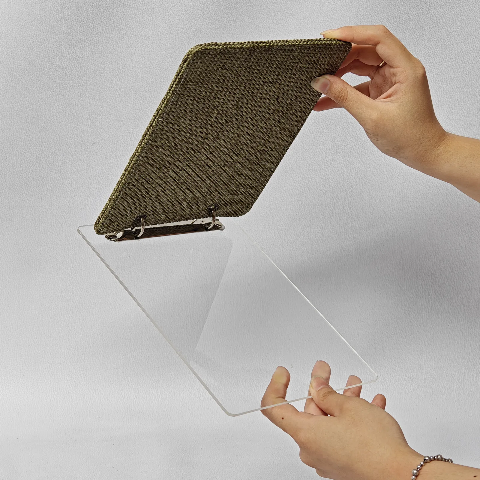 Hands opening a canvas menu cover to show the clear acrylic page and metal ring binding.