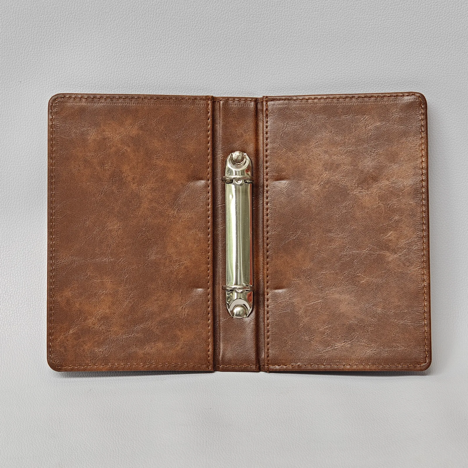 Interior view of an open brown leather menu cover showing a silver-tone 2-ring binder mechanism.
