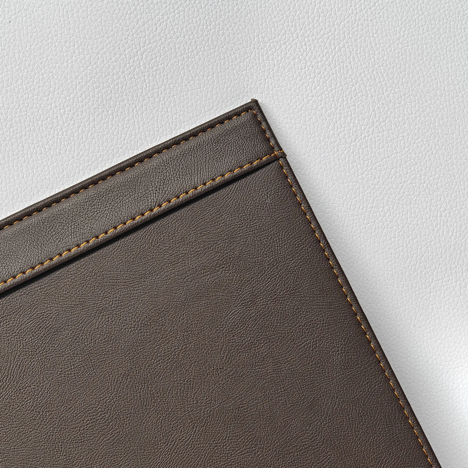 Close-up of the corner stitching on a dark brown leather folder.