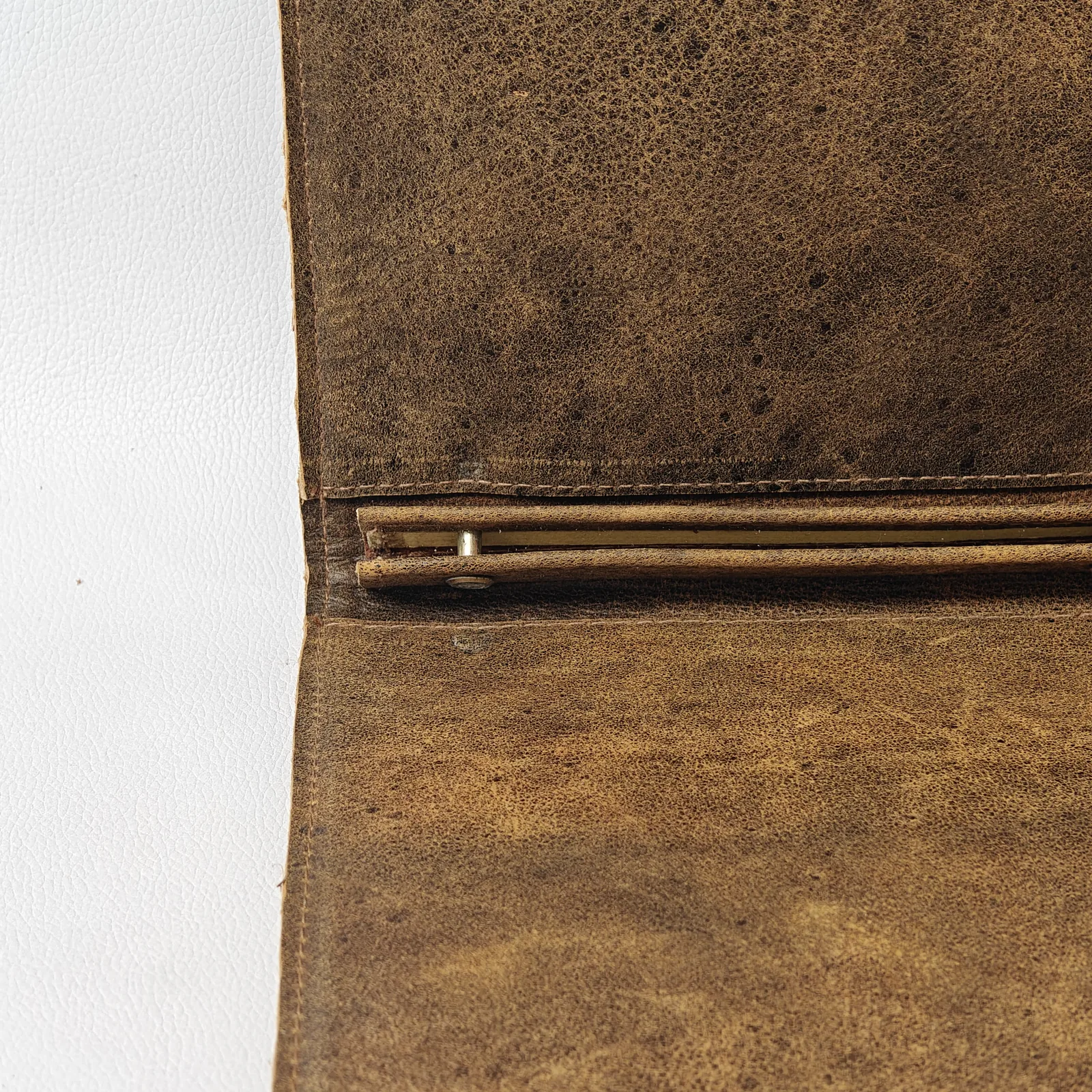 Close-up of the internal spine of the leather cover with a metal screw post for holding pages.