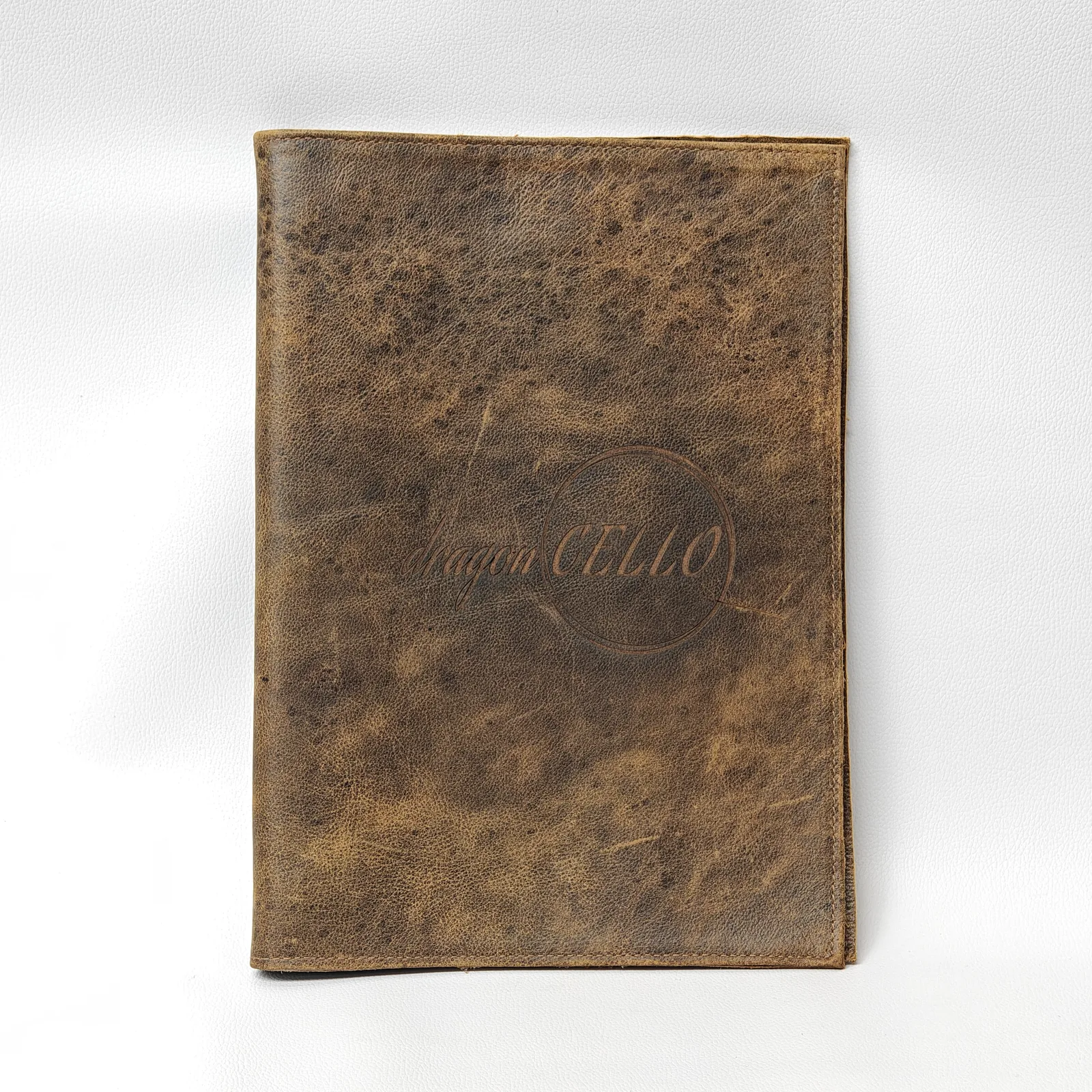 Closed brown leather menu cover with a distressed texture and a central embossed logo.