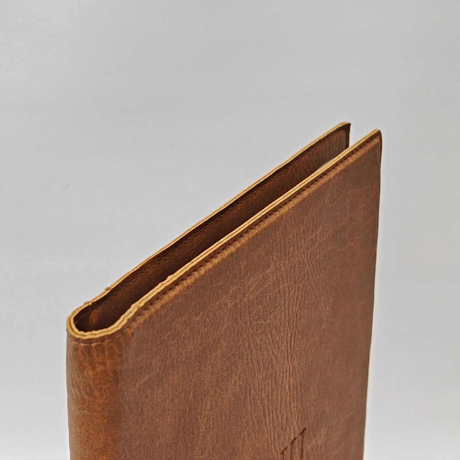 Angled view of the spine of a brown textured menu folder.