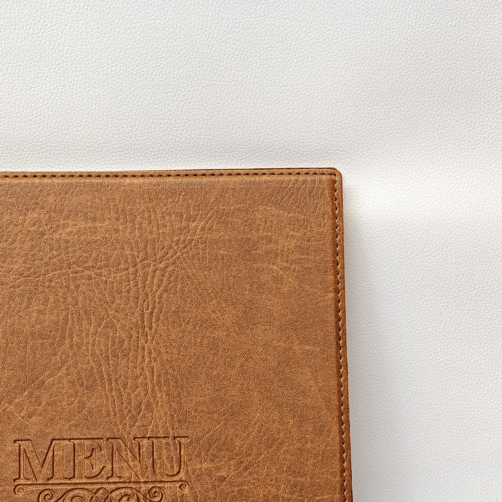 Detail of the top corner and perimeter stitching on a brown textured cover.
