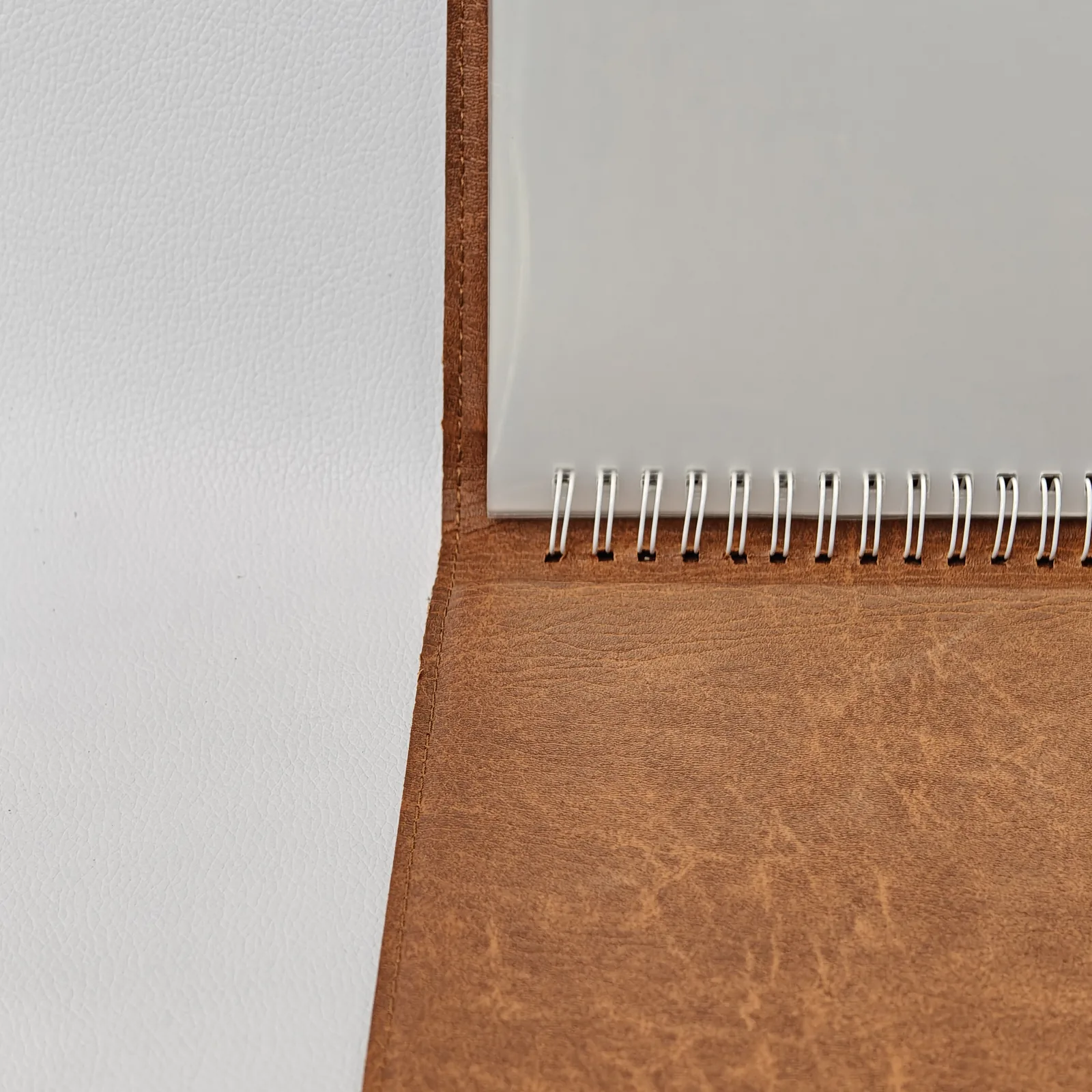 Close-up of the white spiral binding inside a brown textured folder.