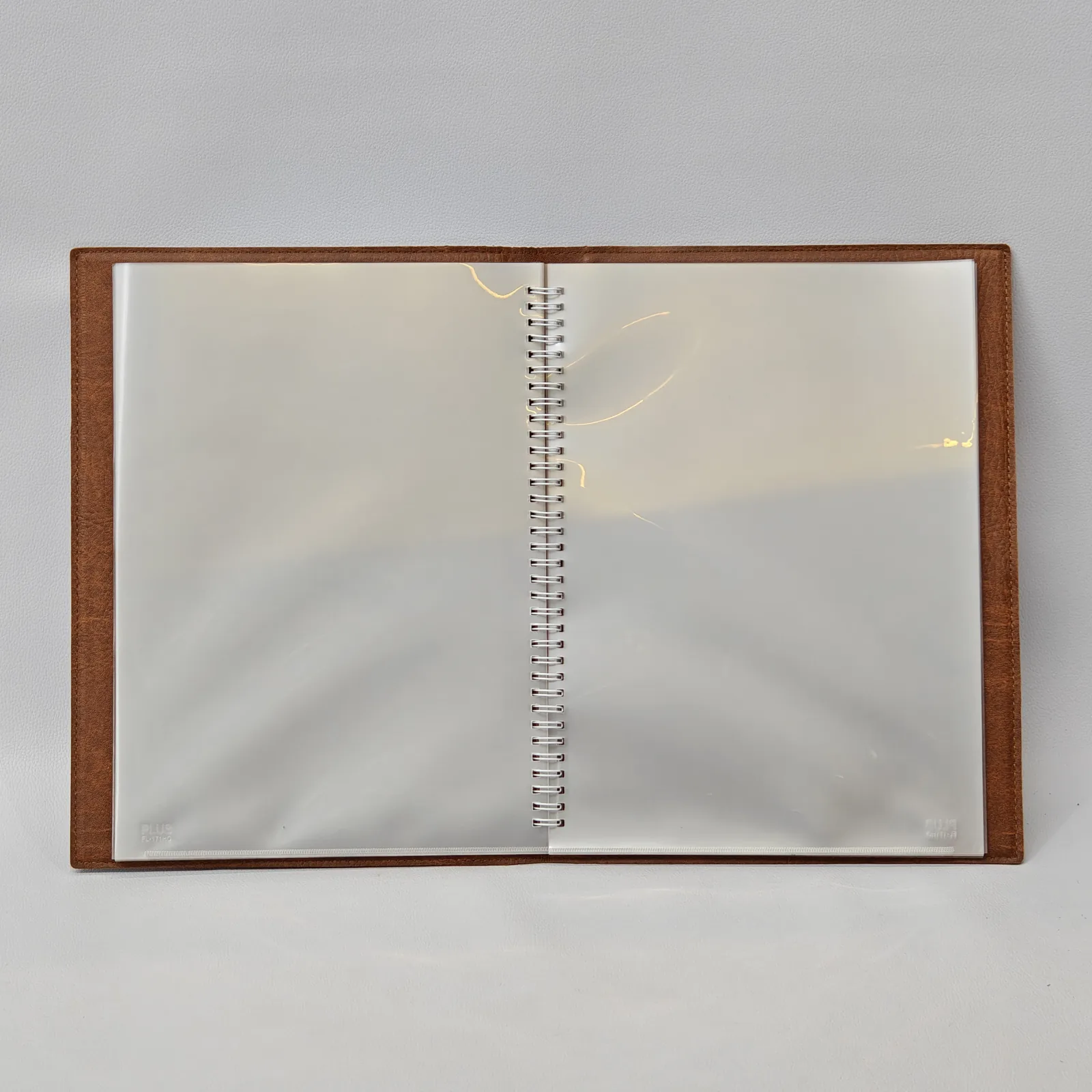 Fully open menu cover displaying two clear plastic sleeves and a central spiral binding.