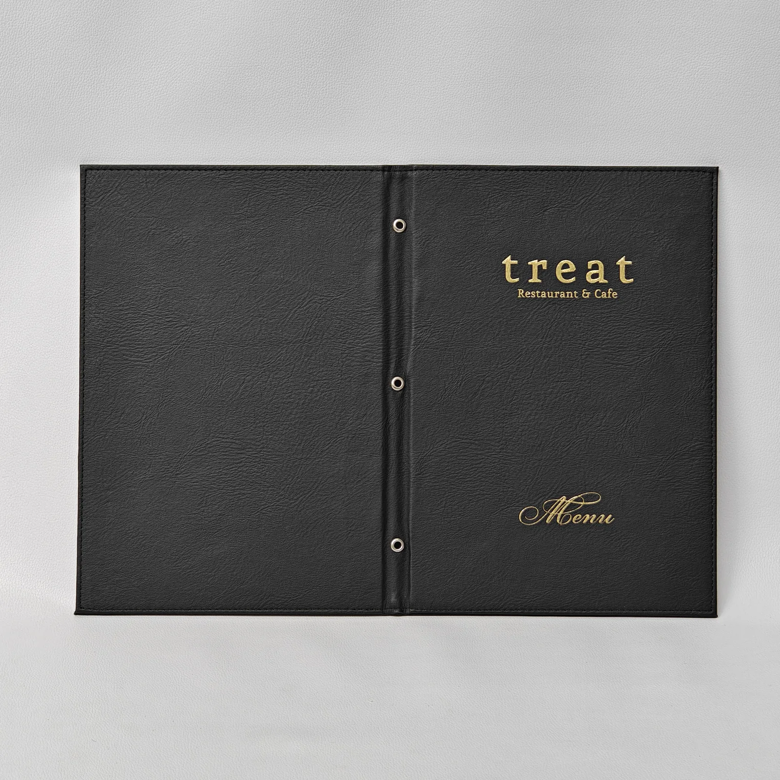Full exterior spread of a black leather menu cover with gold foil lettering on the front panel.