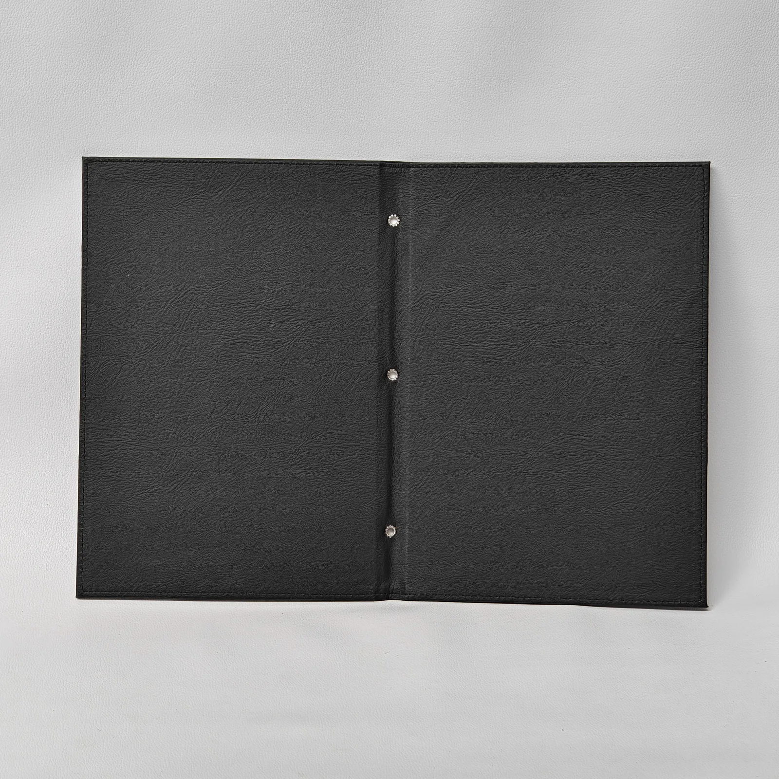 Interior view of an open black leather menu cover showing the inner lining and three silver binding posts.