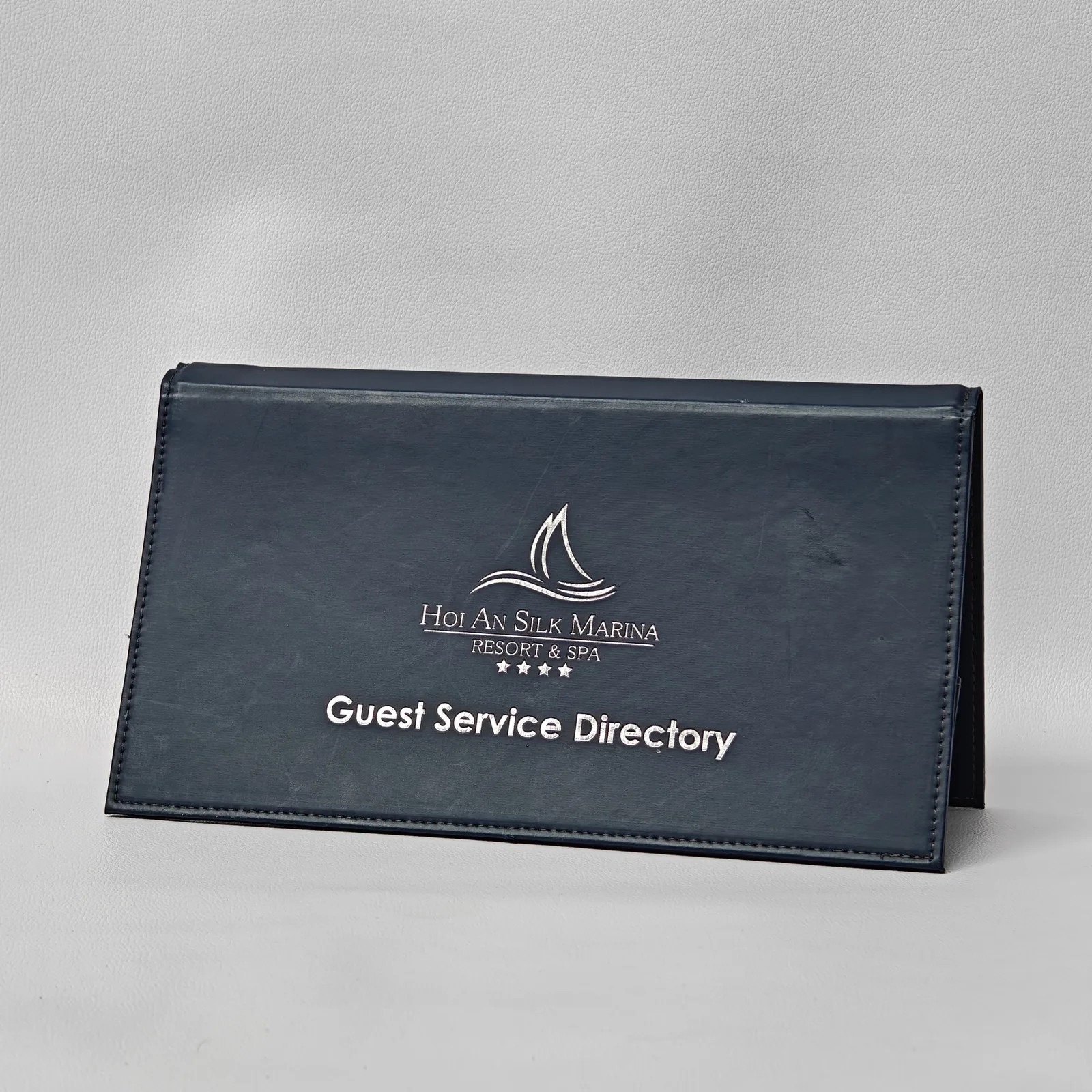 Front view of navy blue leather hotel directory cover with embossed emblem