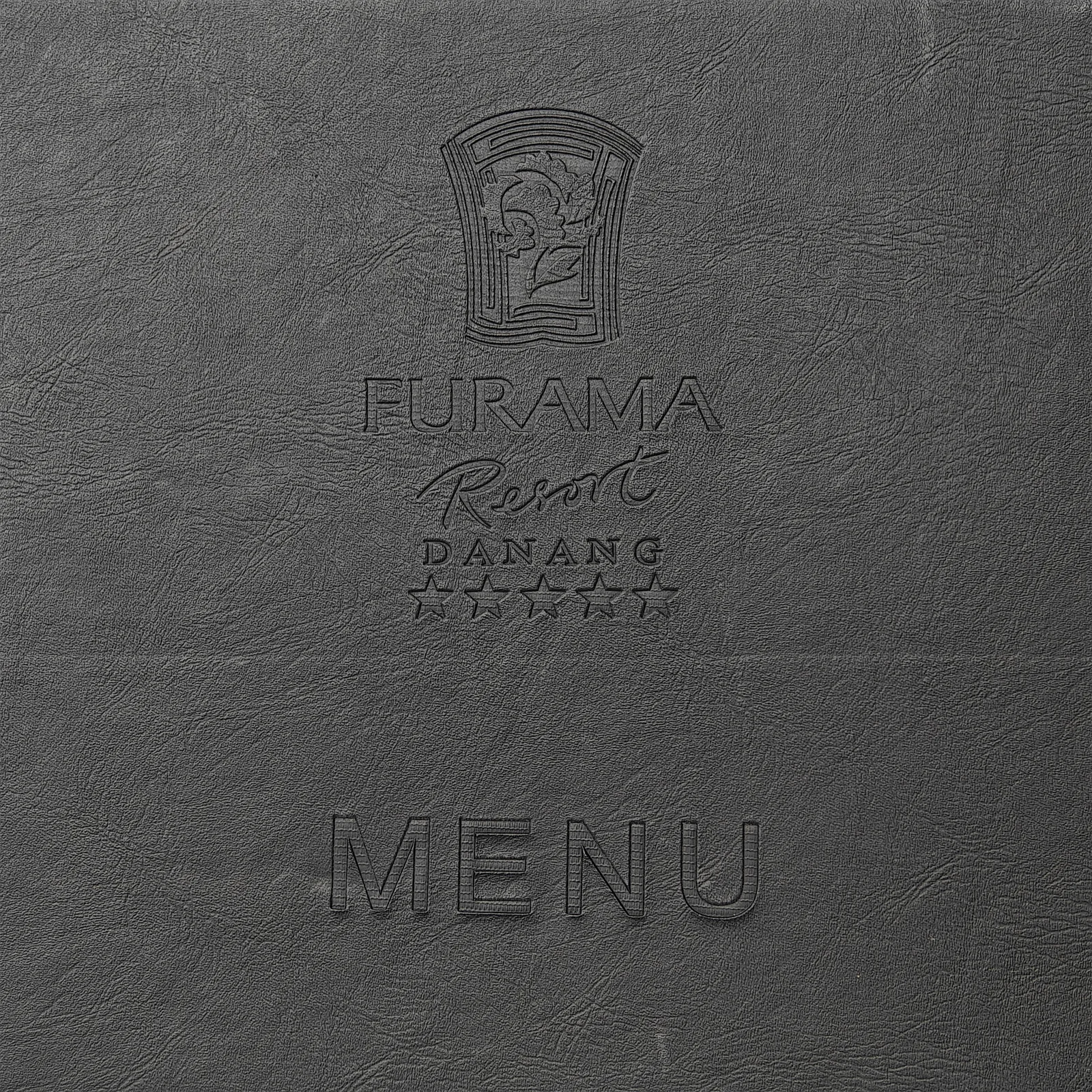 Close-up of debossed logo and the word MENU on black textured leather.