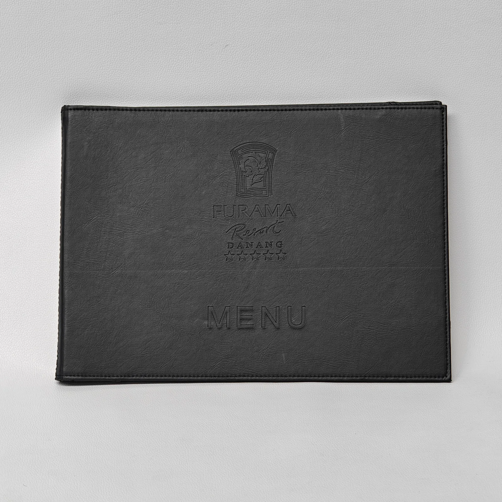 Front view of a black textured leather menu cover with debossed logo and text.