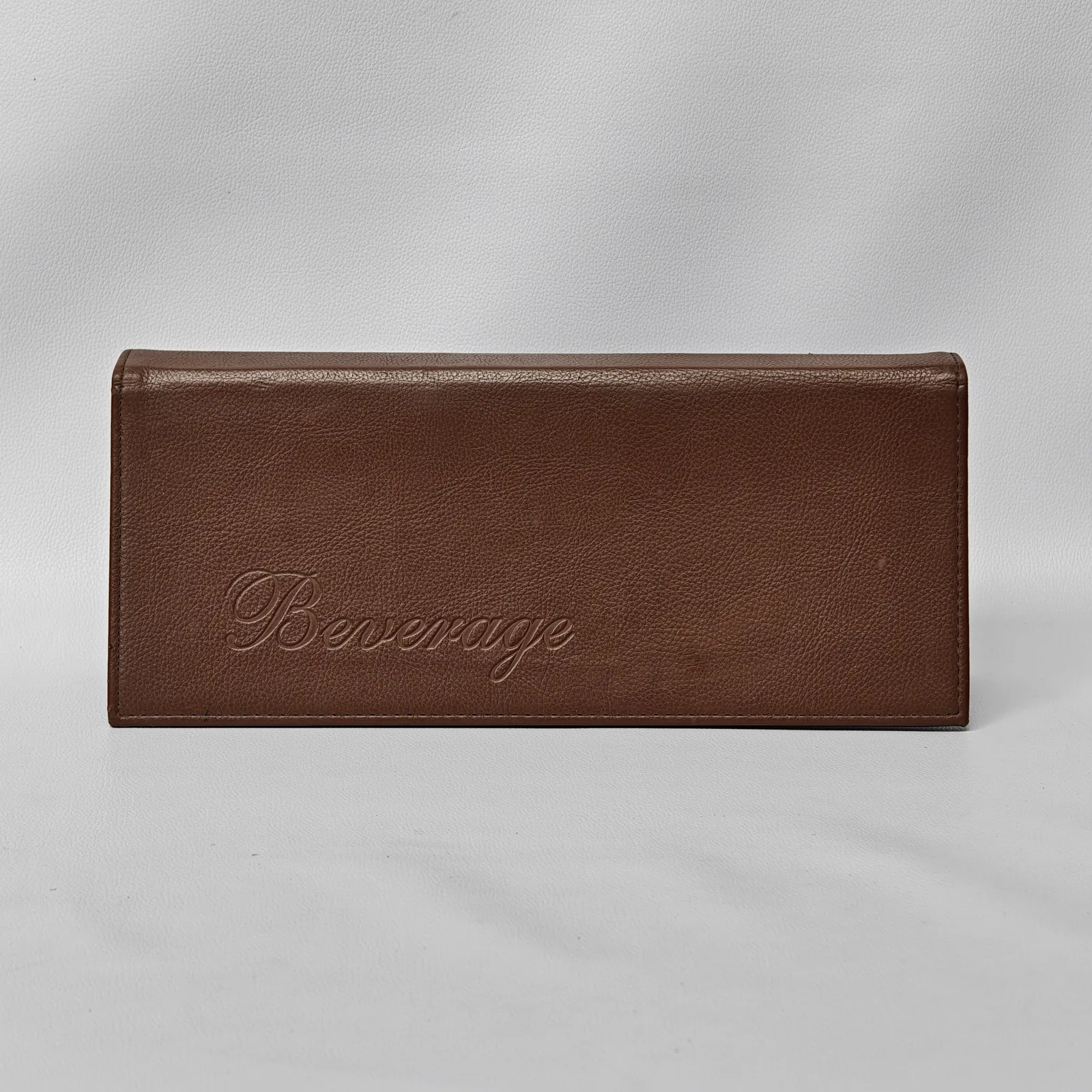 Brown pebbled leather beverage menu cover with debossed script text.
