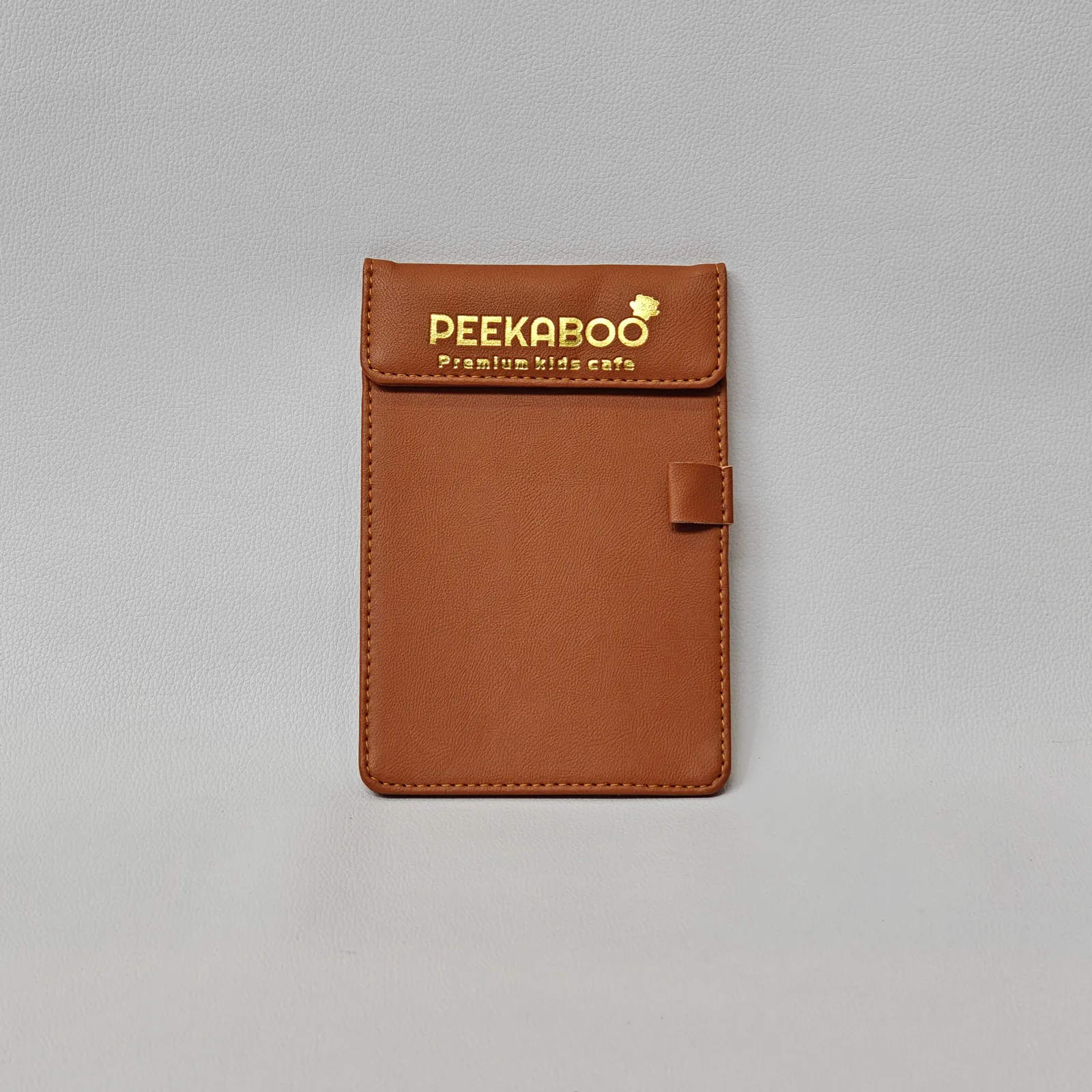 Tan leather bill presenter with gold foil branding and magnetic closure flap