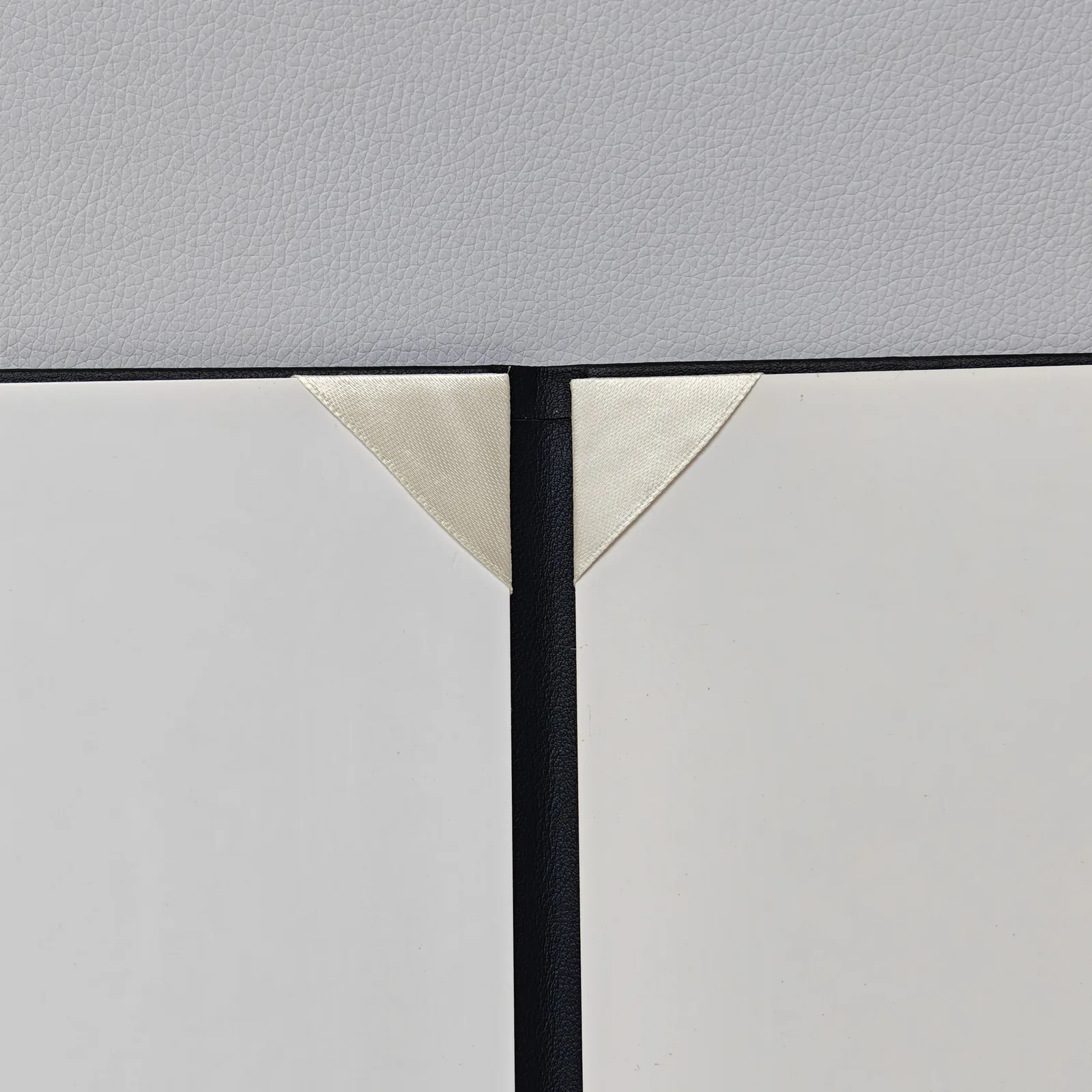 Close-up of the interior spine and cream ribbon corner holders on white panels.