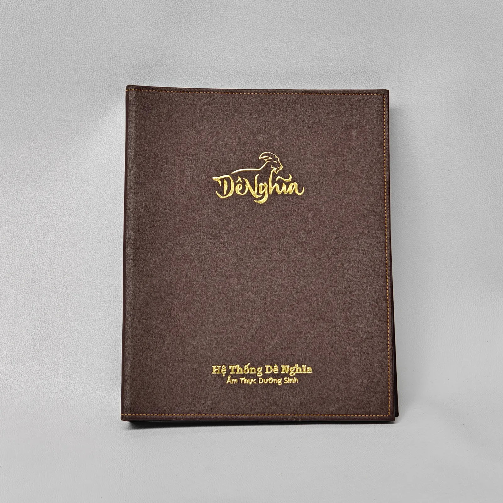 Front view of a brown smooth leather menu cover with gold foil stamped logo and text.