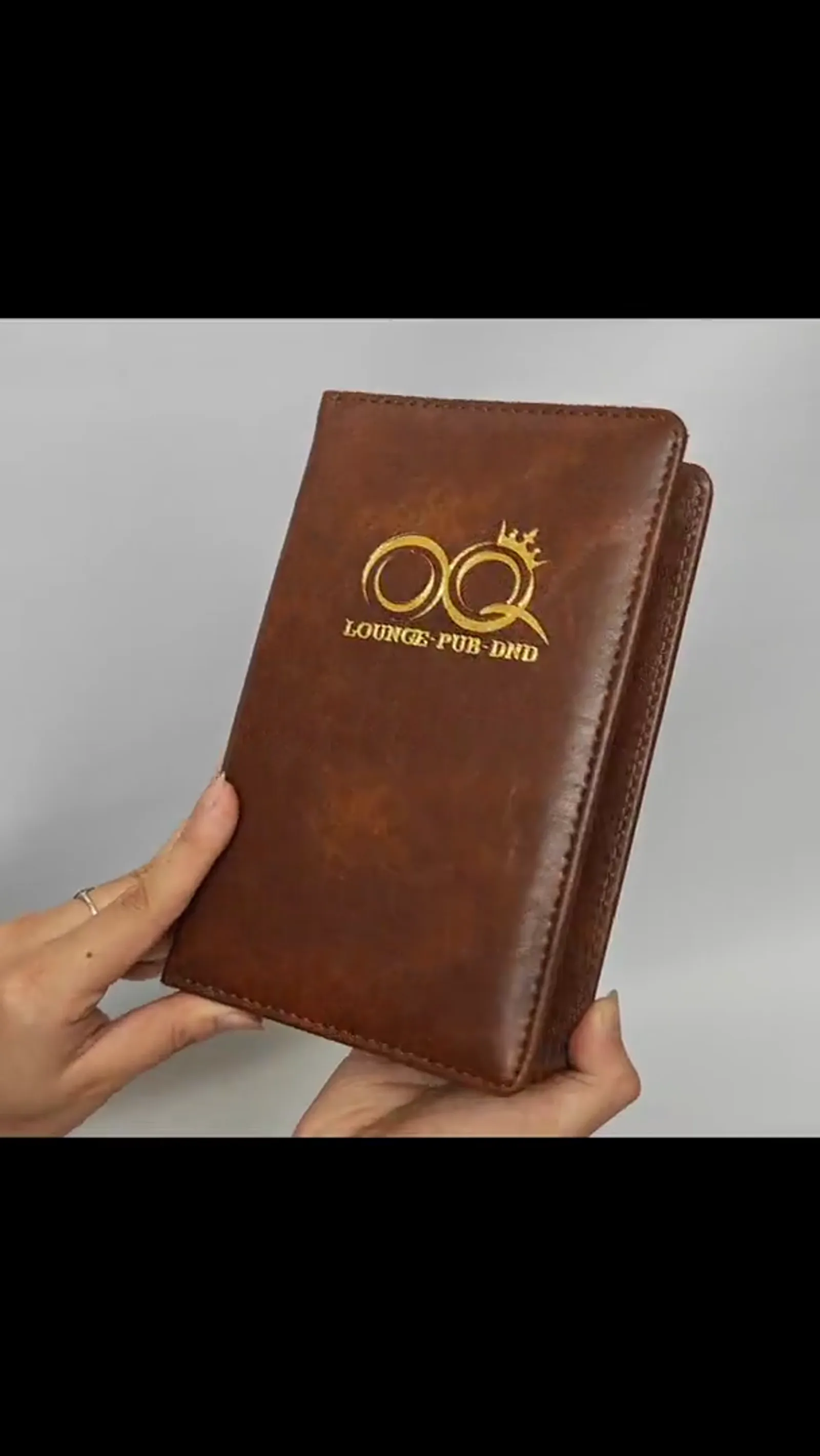 Hands holding leather presenter demonstrating scale and tactile quality