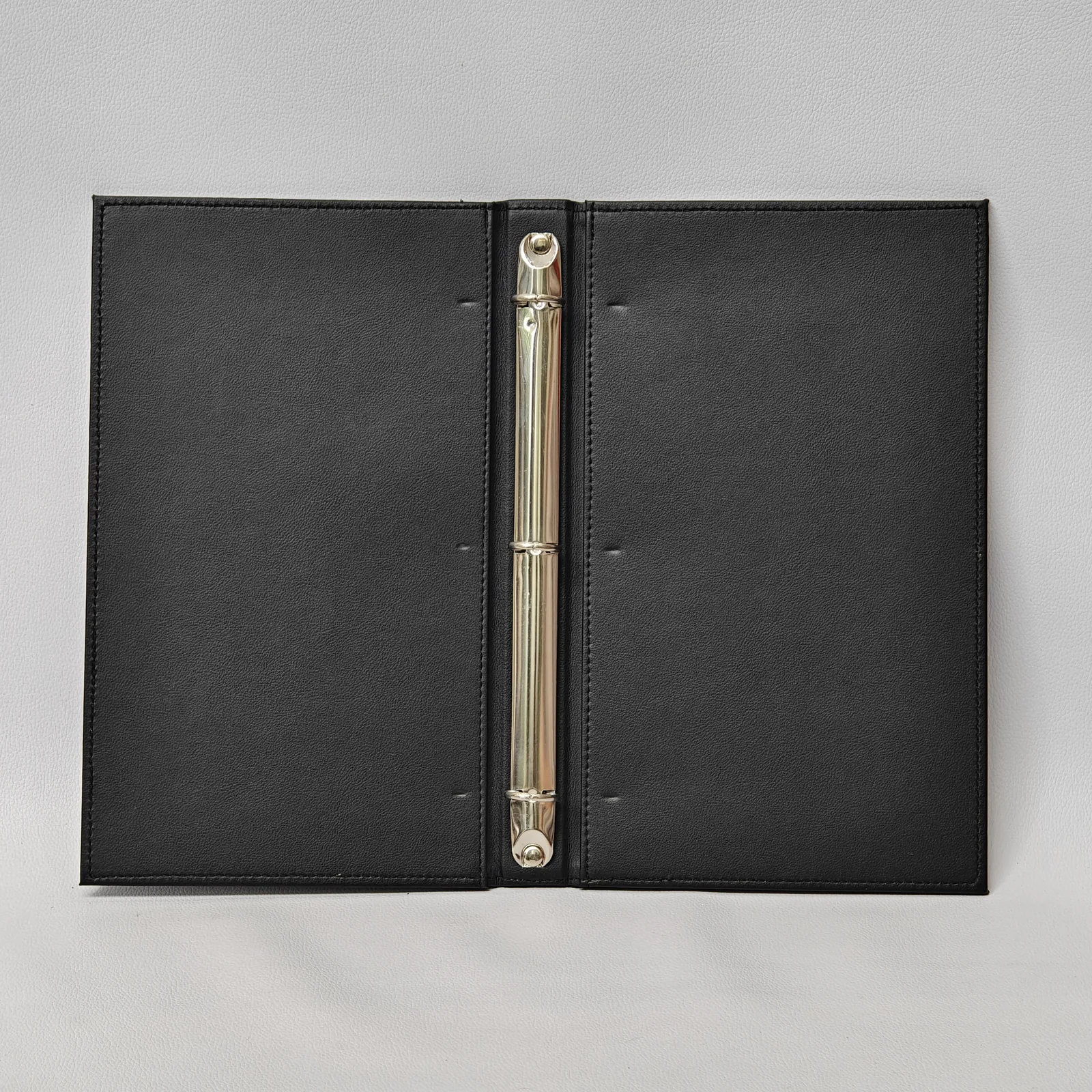 The interior of an open black leather binder featuring a silver three-ring mechanism.