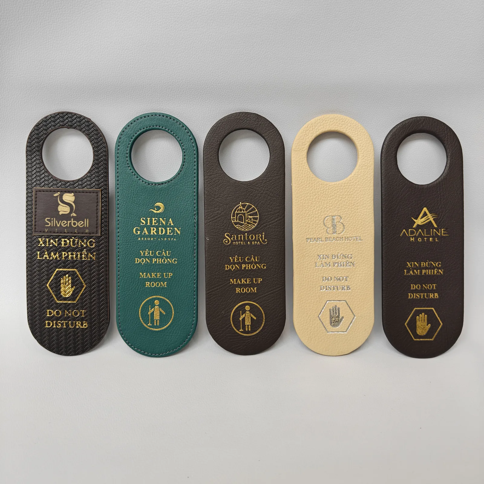 Collection of five pebbled leather hotel door hangers in coordinated colors