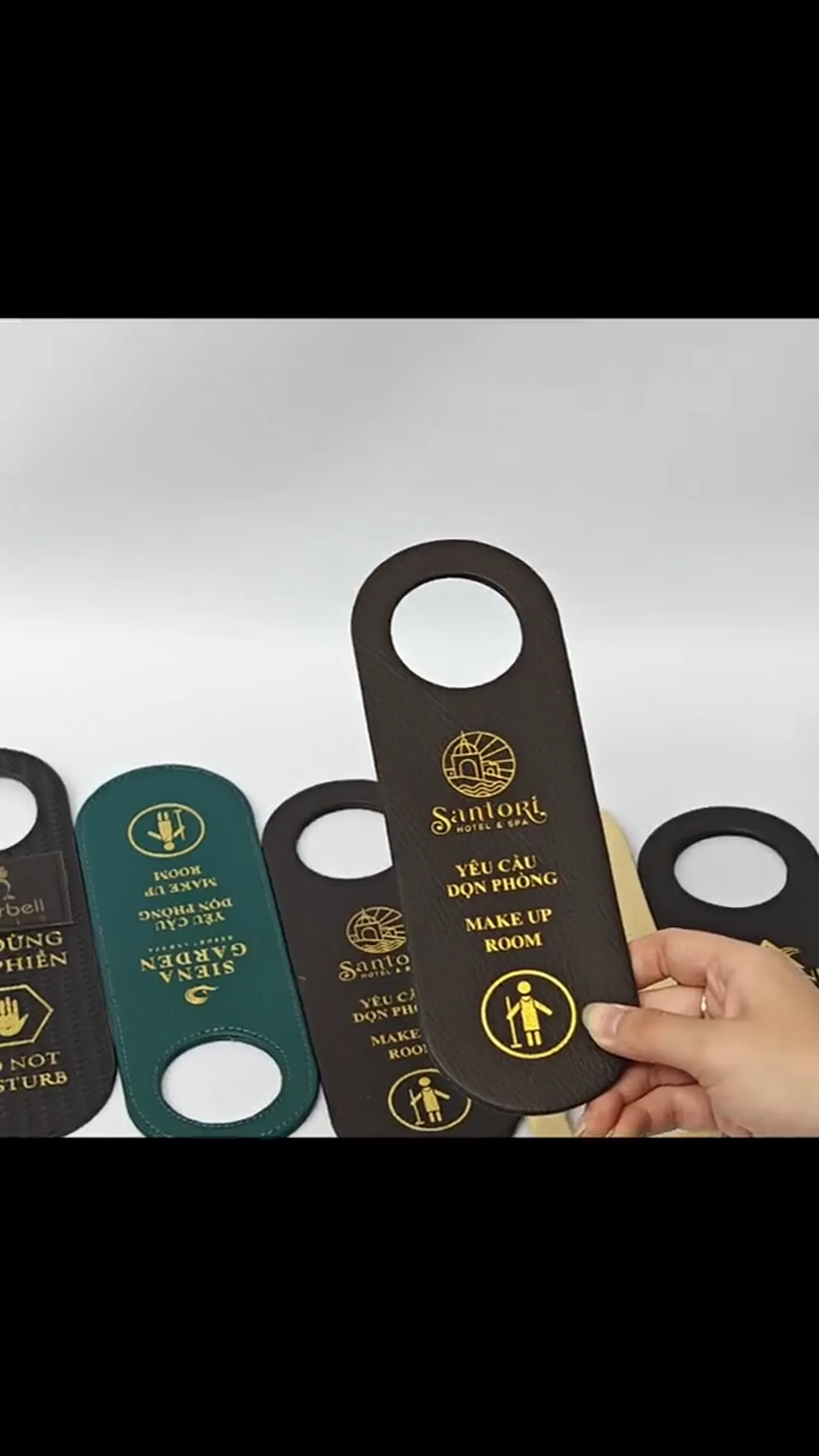 Multiple door hangers held in hand showing scale and texture variety