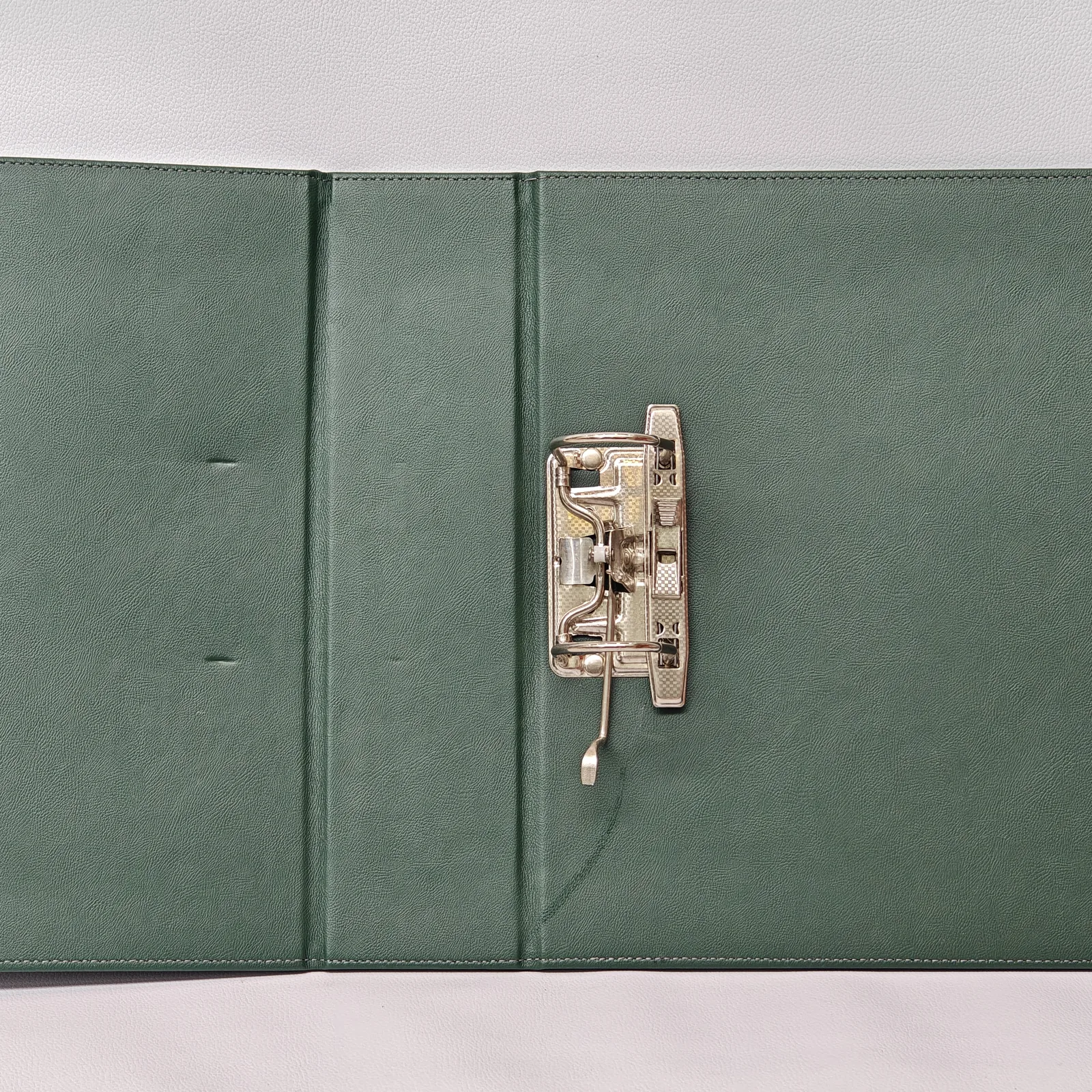 Open green leather binder showing the internal metal lever arch mechanism.
