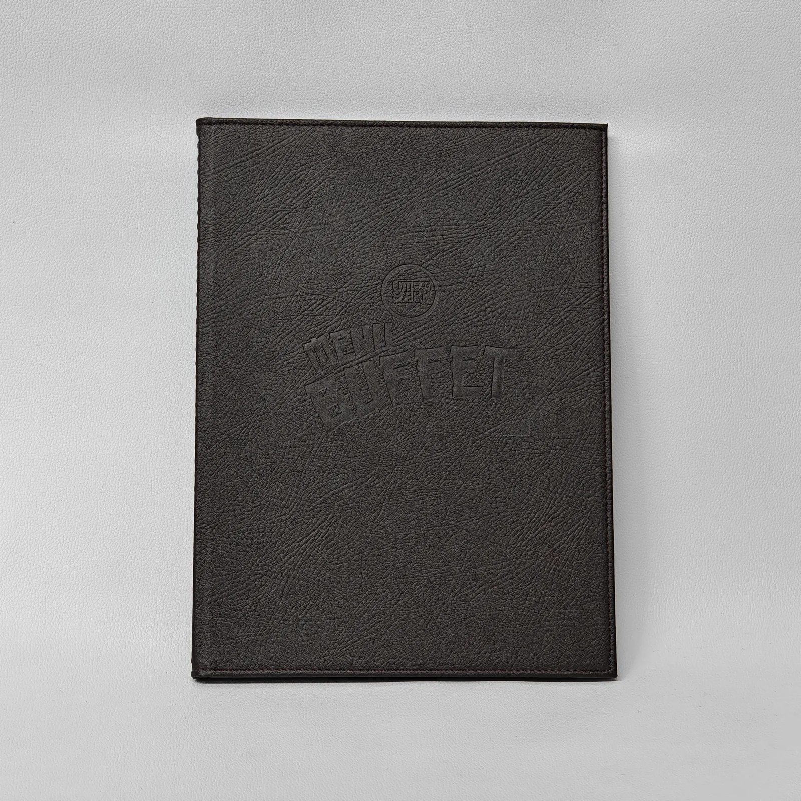 Dark brown textured leather menu cover with a debossed logo and perimeter stitching.