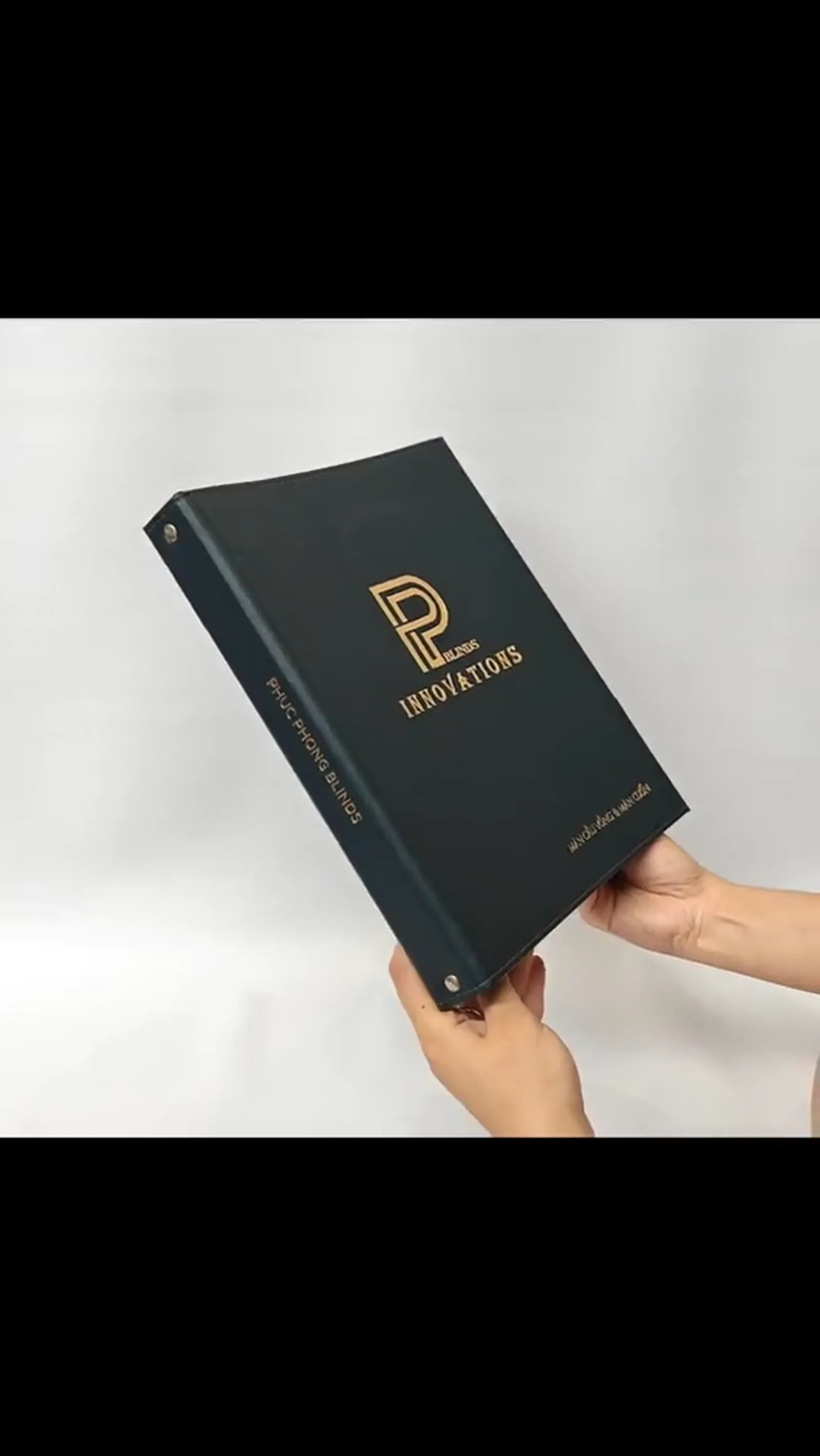 Portfolio binder held by hands showing handling size and pebbled leather texture