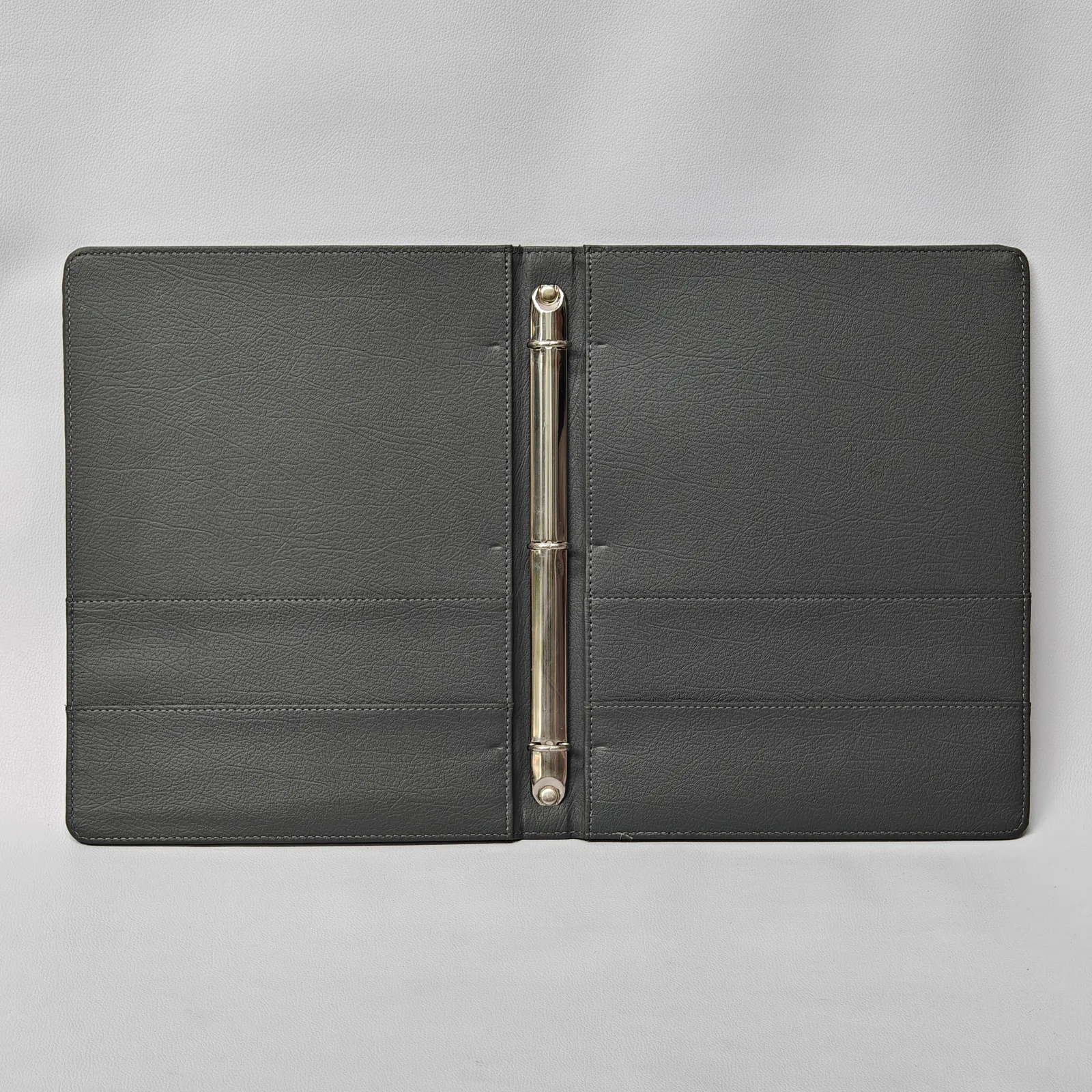 Interior of a black leather binder showing a silver three-ring mechanism and horizontal pockets.