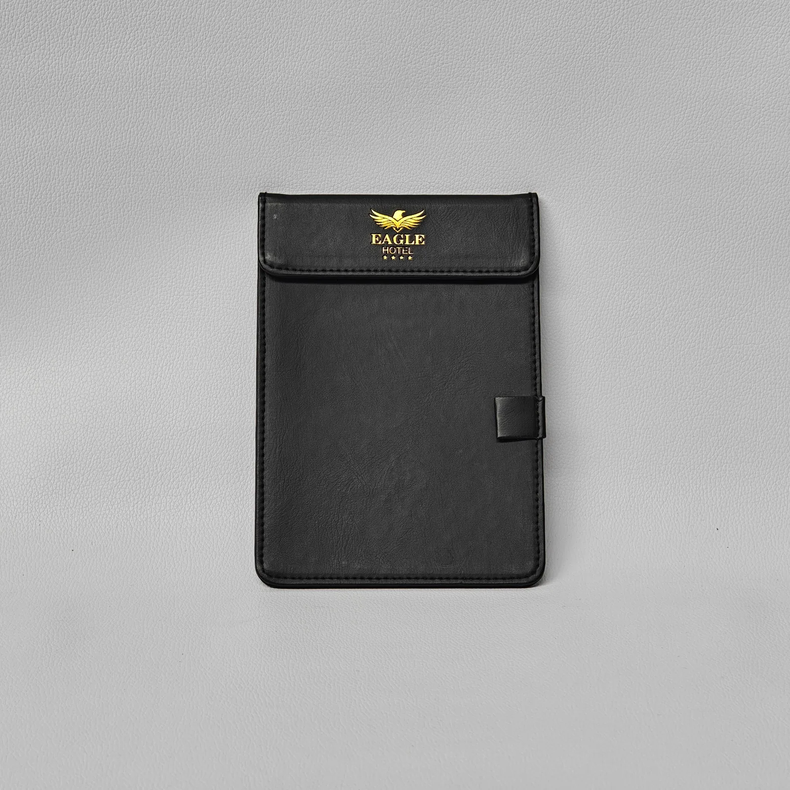 Large taupe leather menu cover with gold foil logo and stitched handles