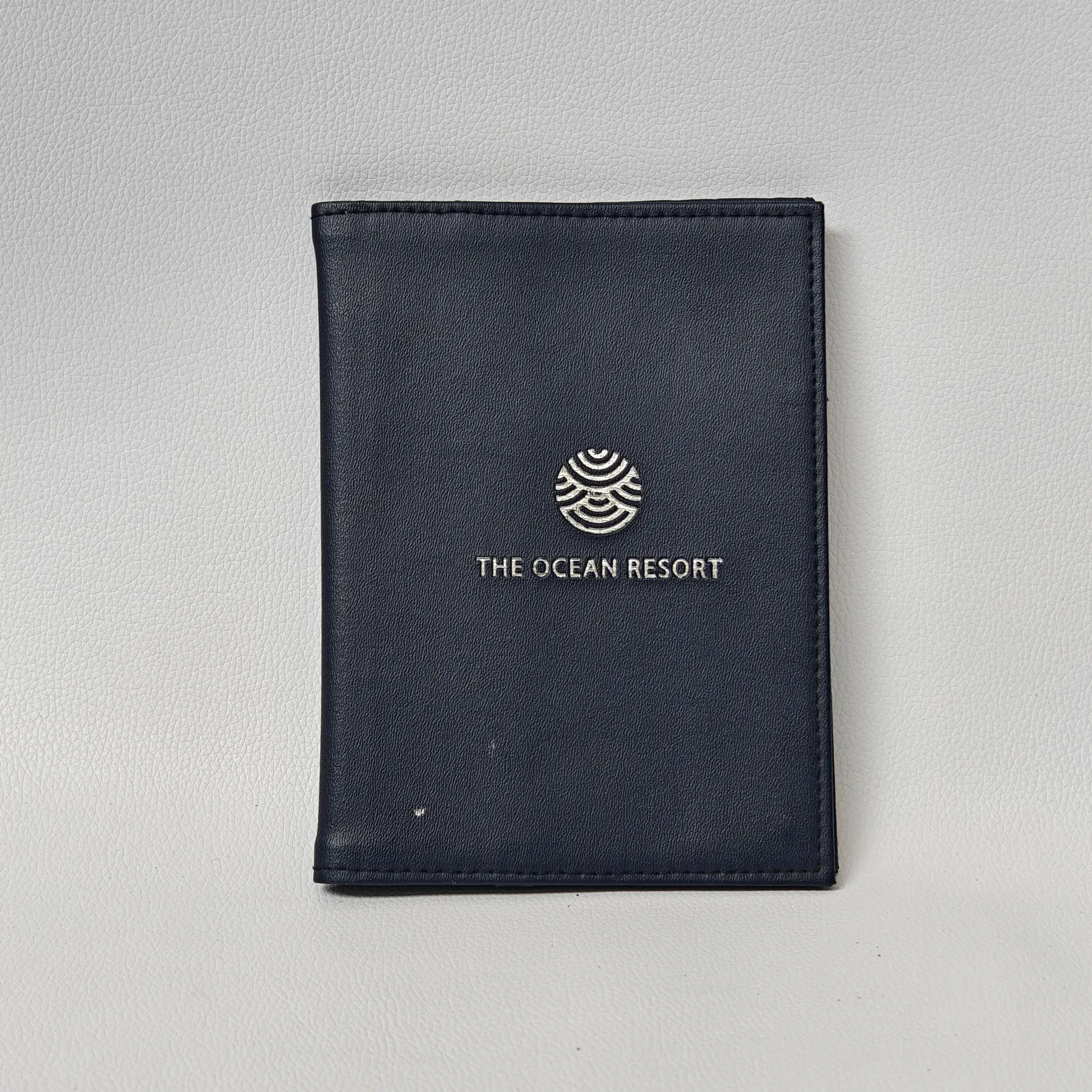 Navy leather bill presenter with centered silver embossed resort branding