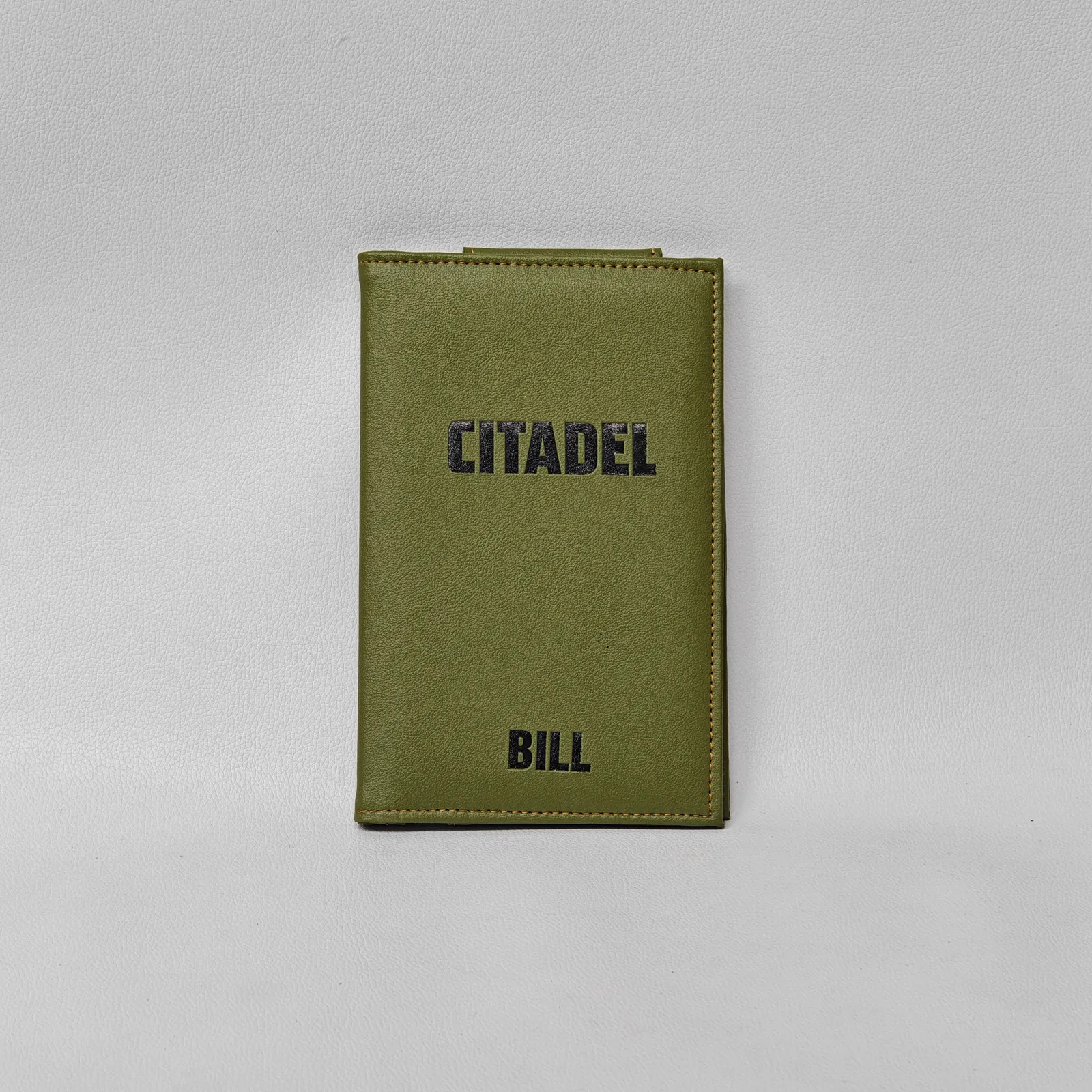 Closed olive green leather check presenter with debossed text and orange perimeter stitching.