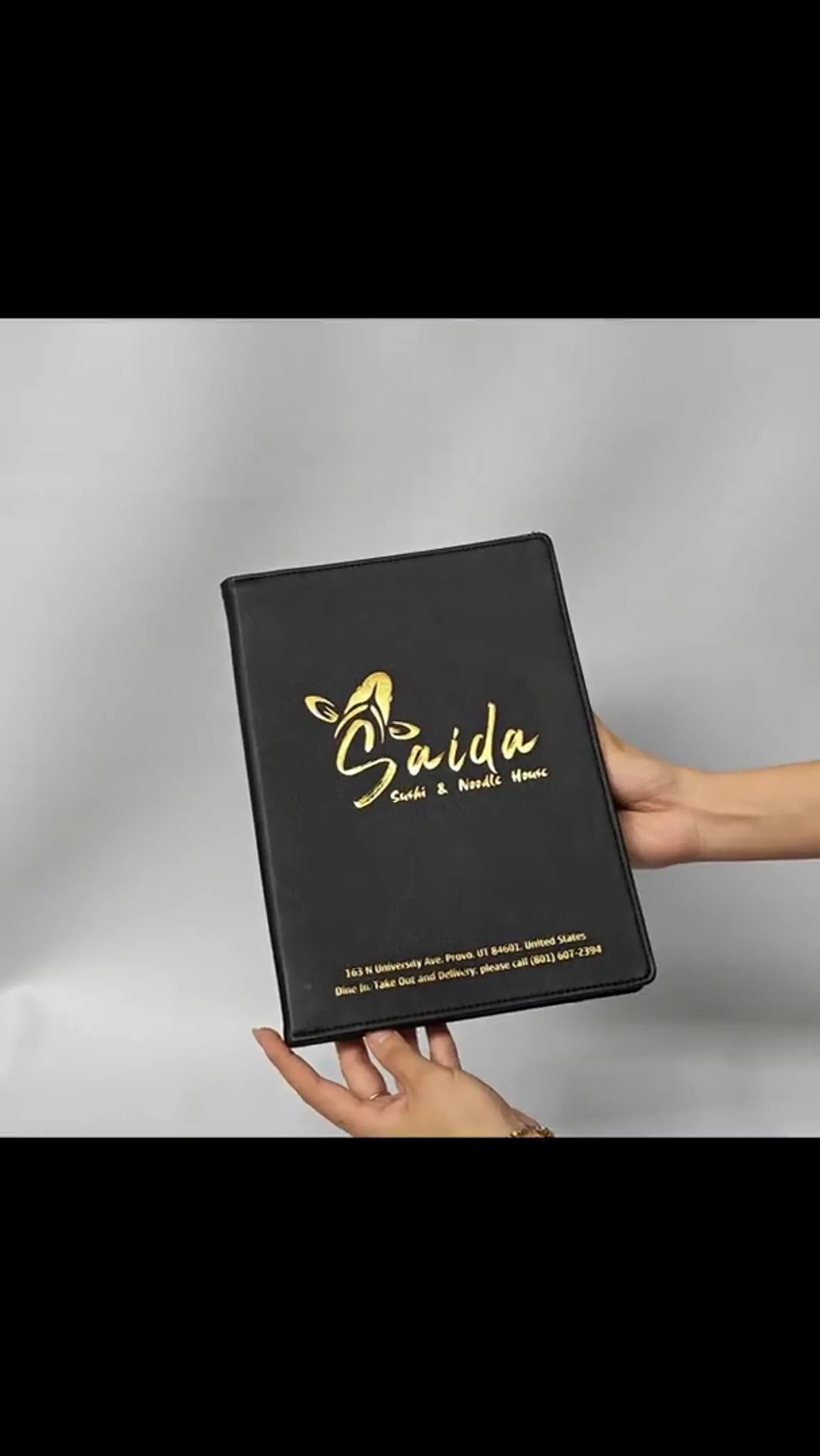 Hands holding open leather menu cover displaying interior construction