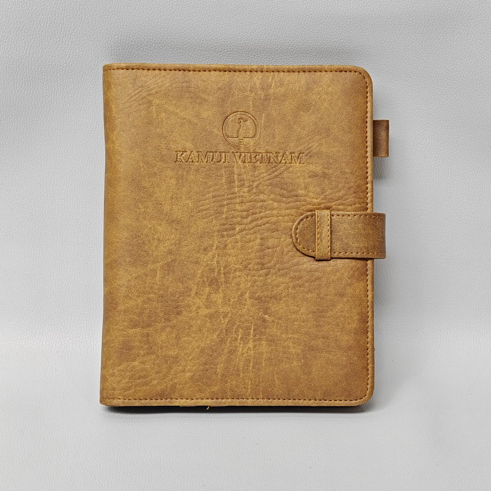 Tan leather notebook cover with embossed logo and elastic band closure