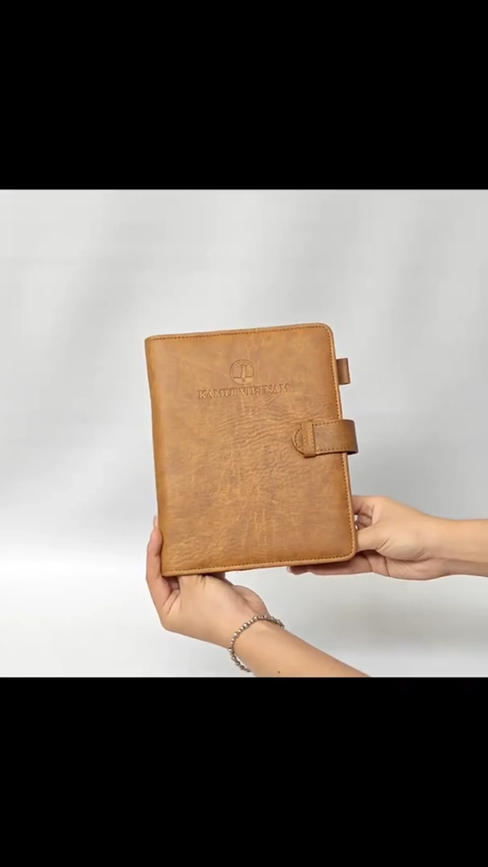 Person holding closed notebook demonstrating size and product proportions