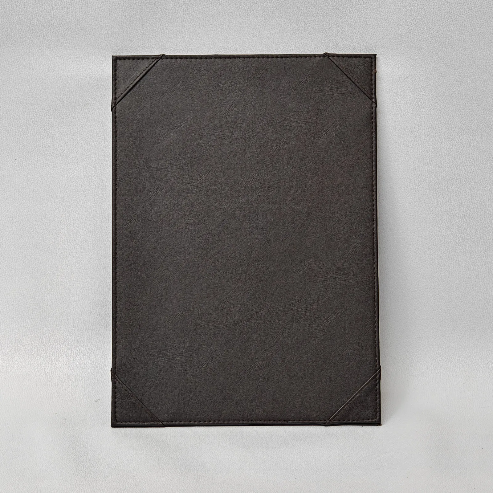 Dark brown textured leather menu board with four corner pockets and perimeter stitching.