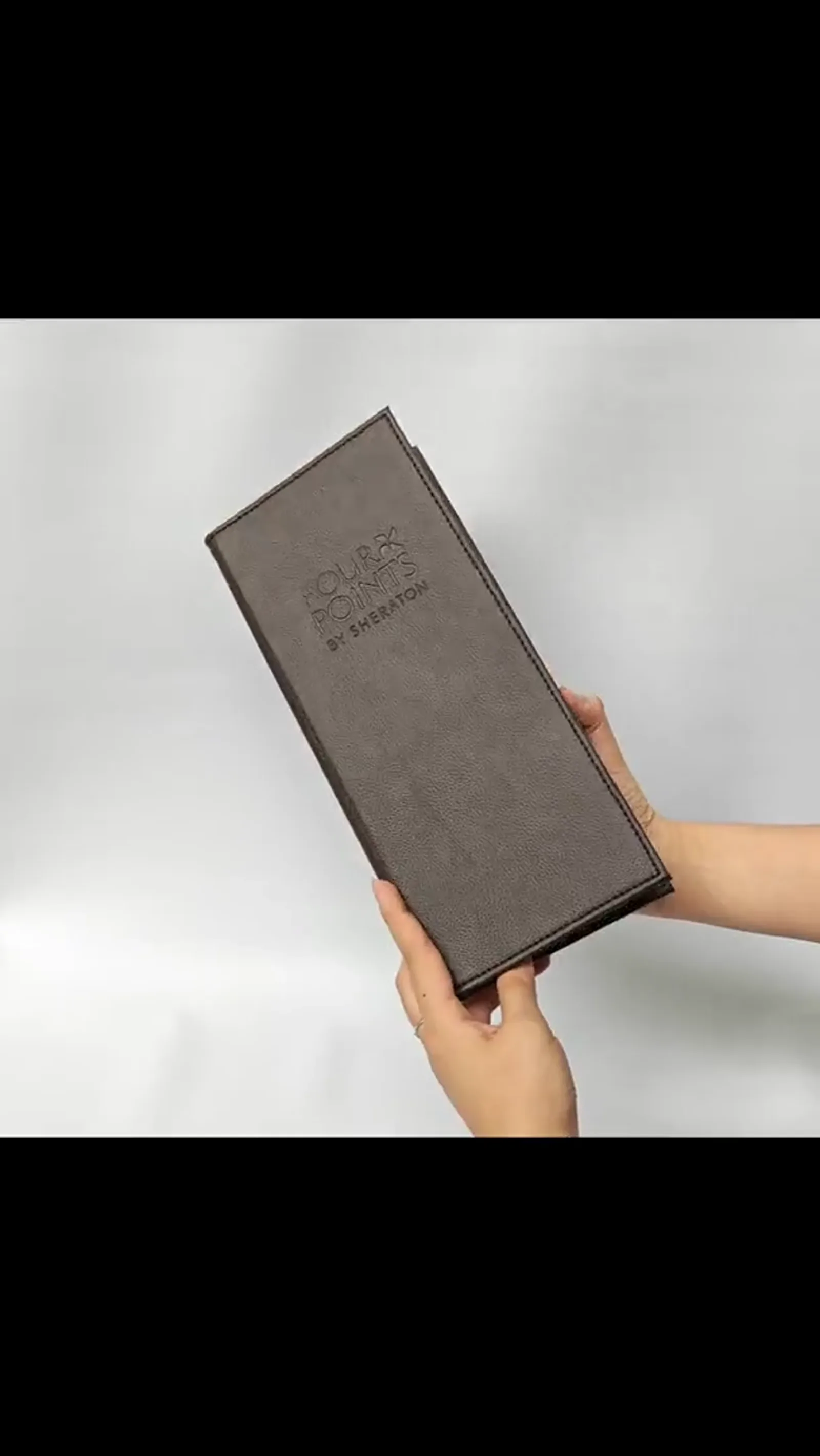 Hand holding taupe bill presenter in use, demonstrating scale and tactile quality