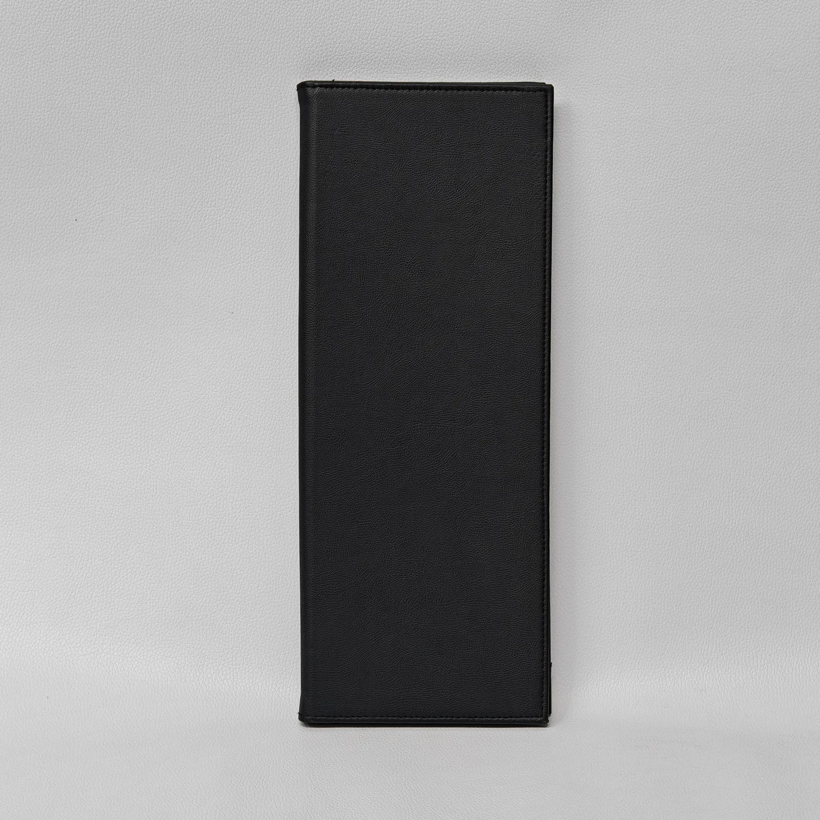 Closed black leather menu cover with a textured finish and perimeter stitching.