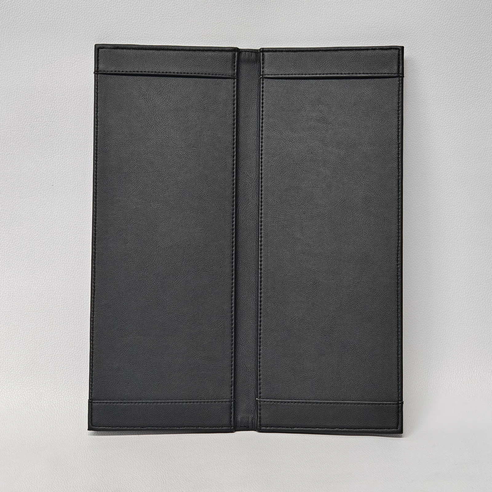 Interior of an empty black leather bifold menu cover with horizontal bands for holding menu inserts.