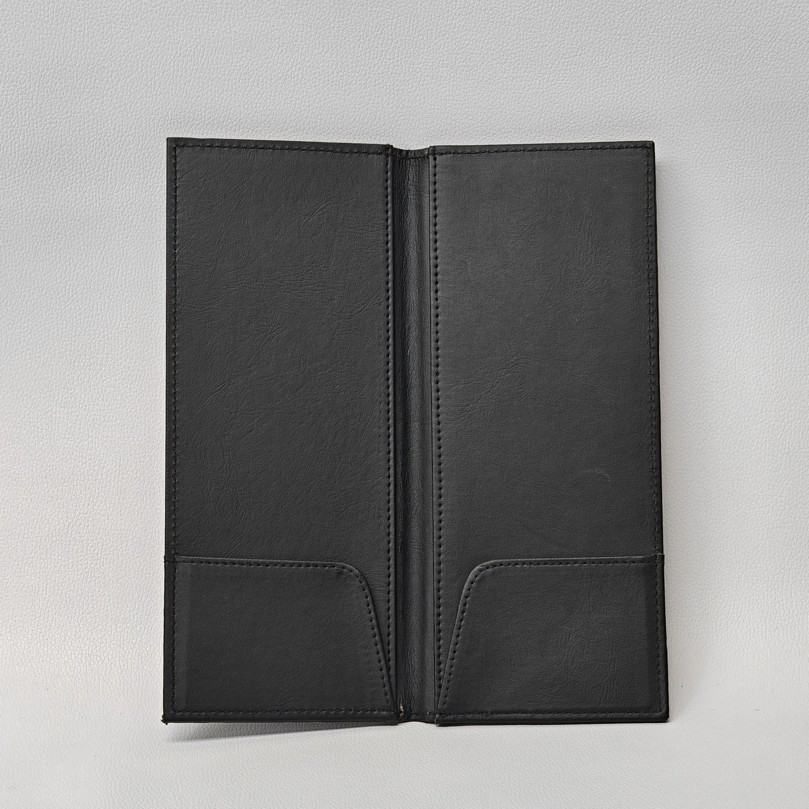 Tall leather menu holder held in hands demonstrating scale and ergonomic handling