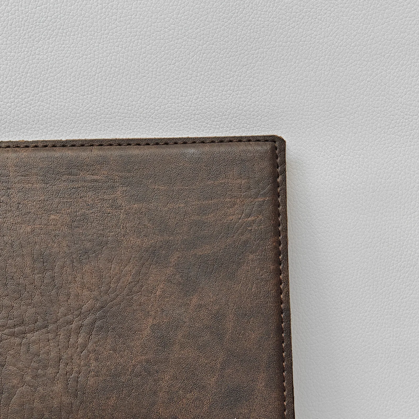 Close-up of the corner stitching and textured brown leather surface.