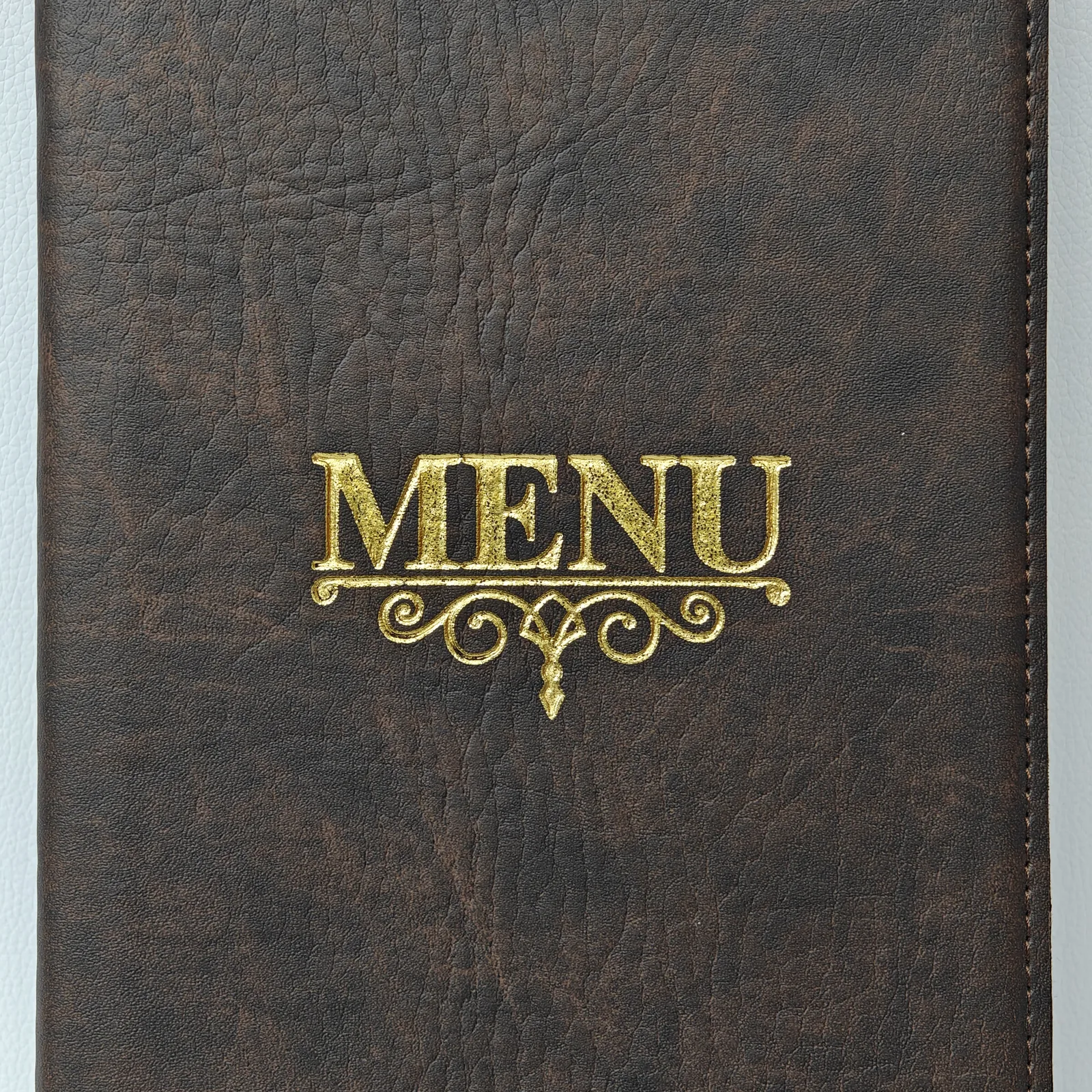 Close-up of the gold foil stamped MENU text with decorative scrollwork.