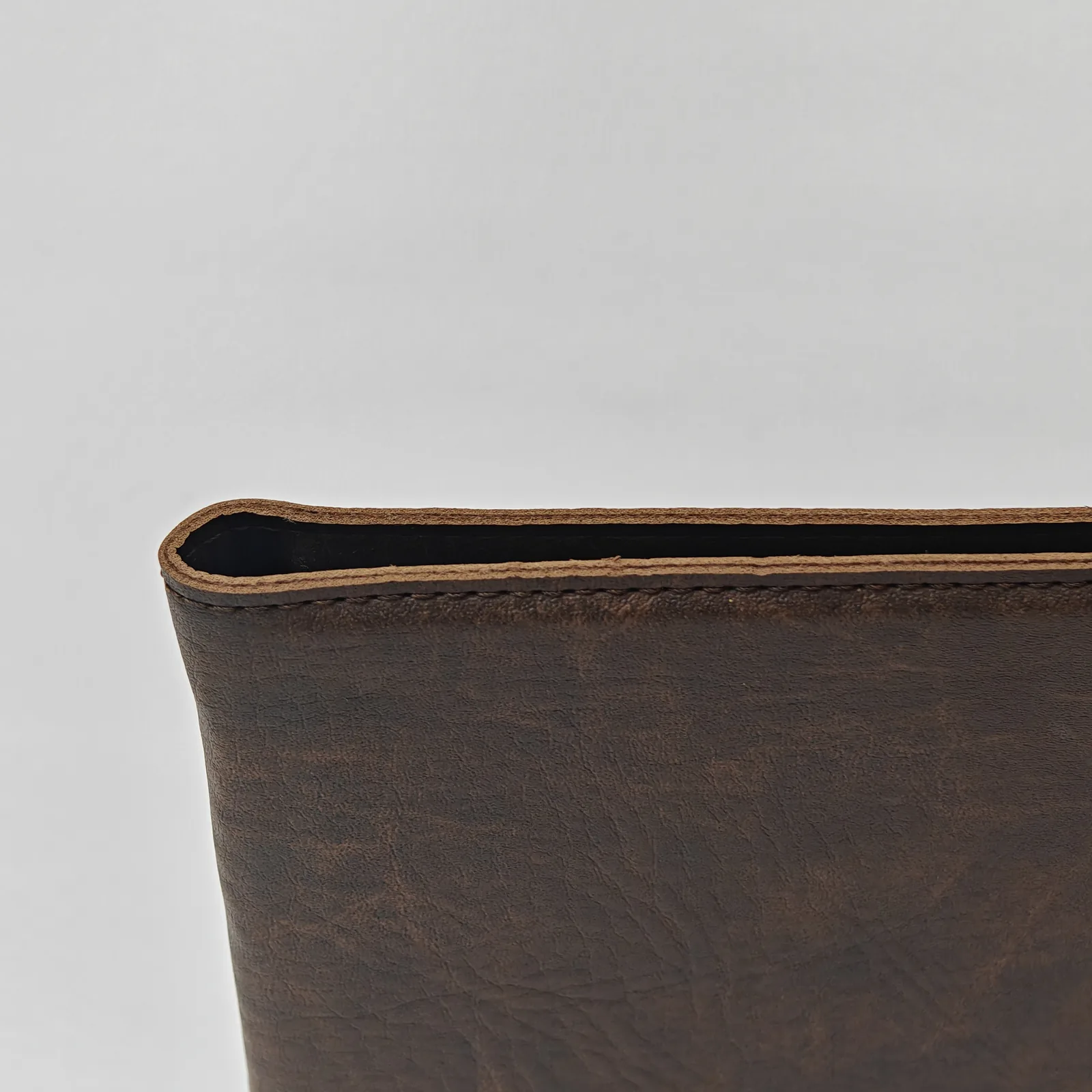 Close-up of the top edge of the leather cover showing the layered construction.
